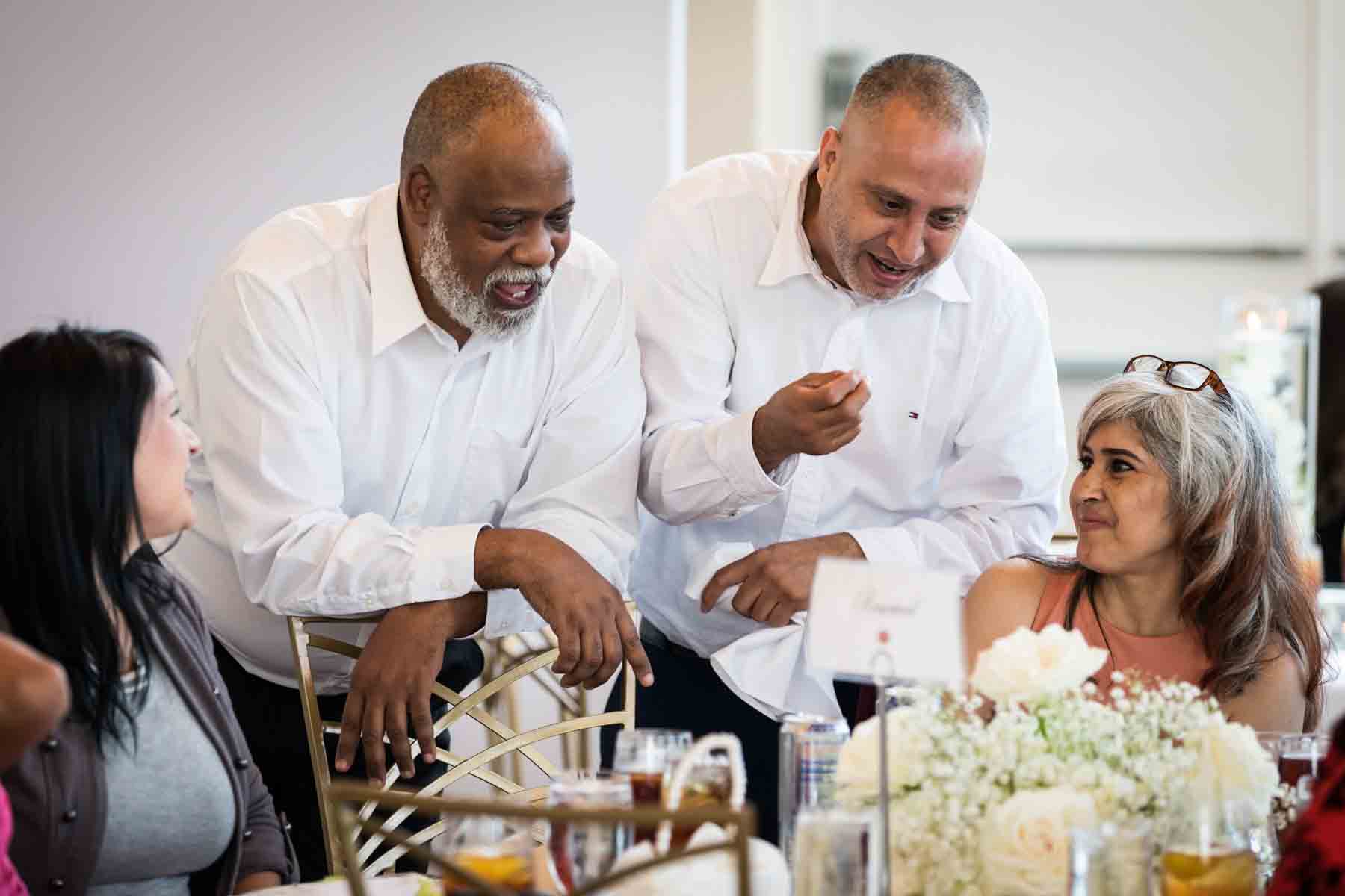 Two men talking to two women at a table during the reception at an Old San Francisco Steakhouse wedding