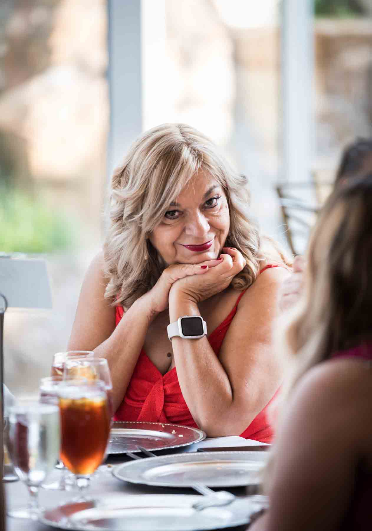 Older woman with blonde hair smiling with head on hands during reception at an Old San Francisco Steakhouse wedding