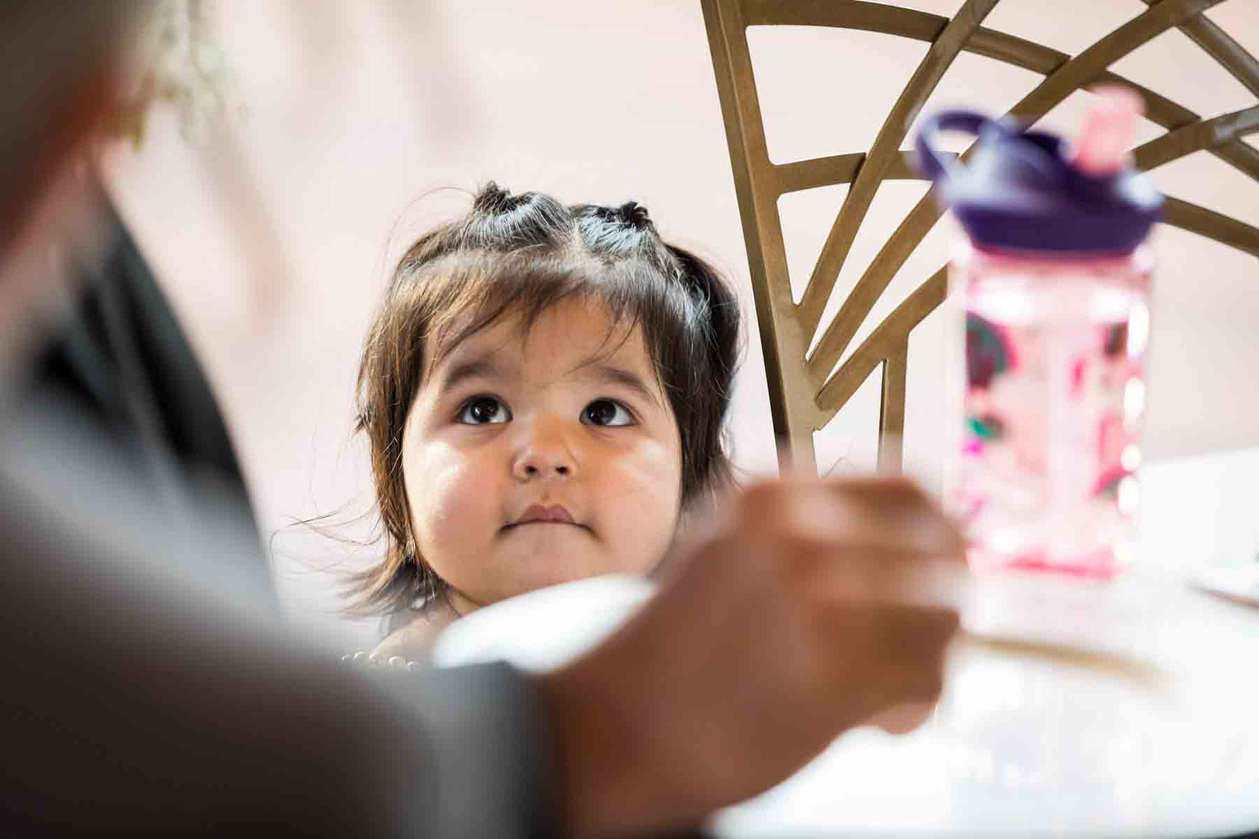 Little girl smiling up at guest at table at an Old San Francisco Steakhouse wedding