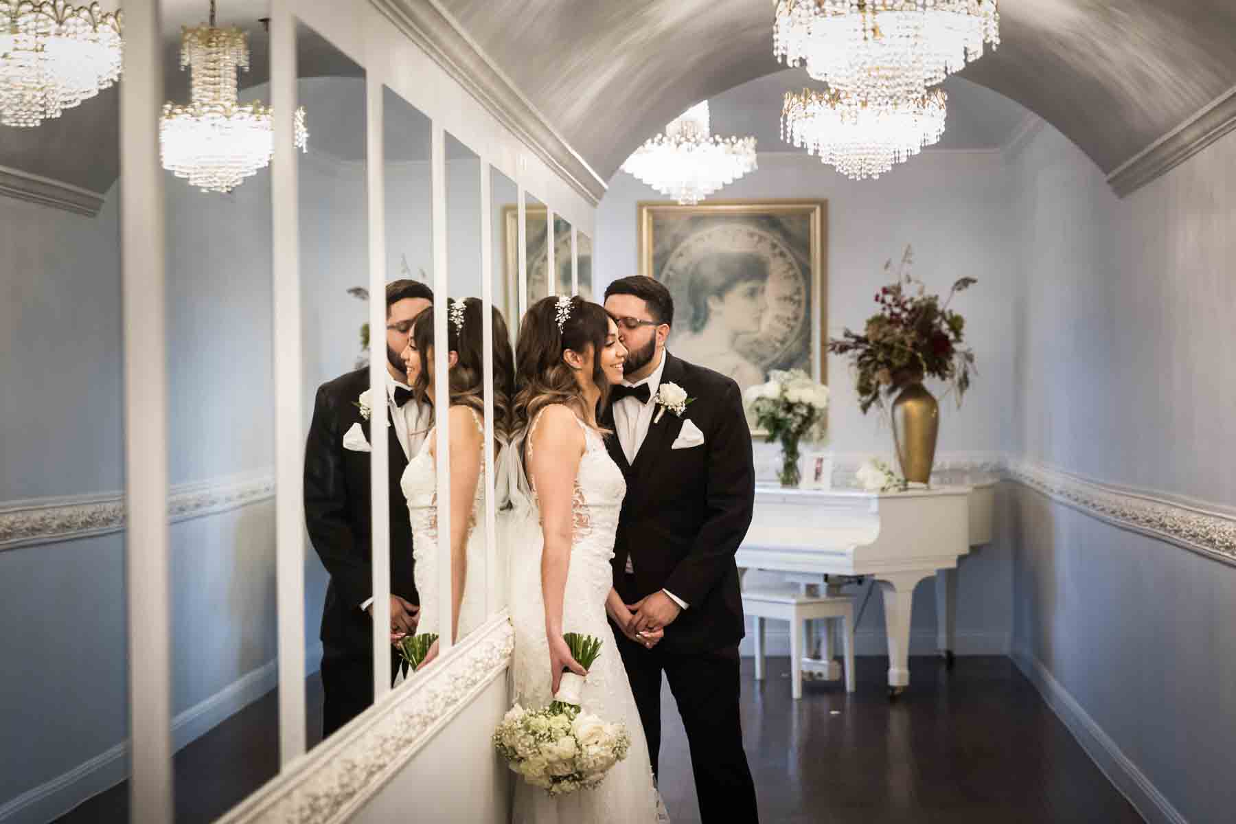 Bride and groom kissing in front of white piano as reflected in mirrors at an Old San Francisco Steakhouse wedding