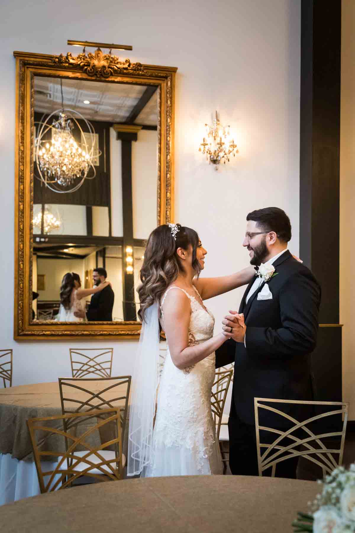 Bride and groom dancing in front of tables and long, gold mirror at an Old San Francisco Steakhouse wedding