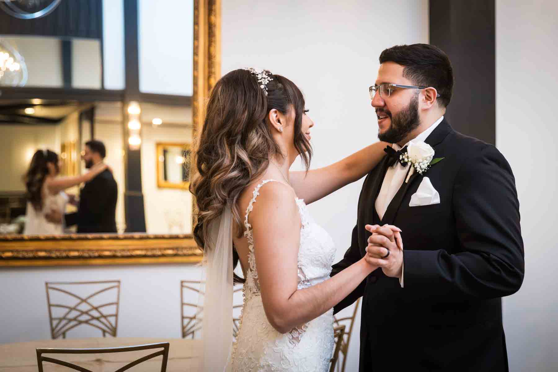 Bride and groom dancing in front of tables and long, gold mirror at an Old San Francisco Steakhouse wedding