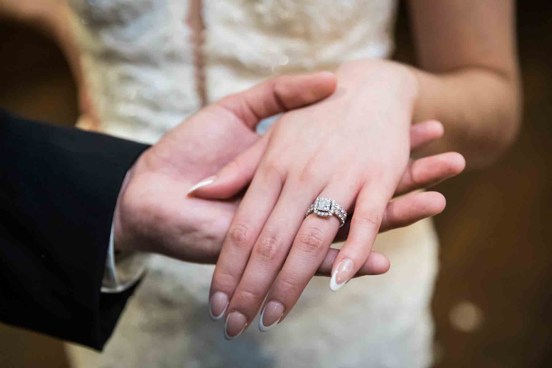 Close up of groom showing bride's hand wearing diamond engagement and wedding rings