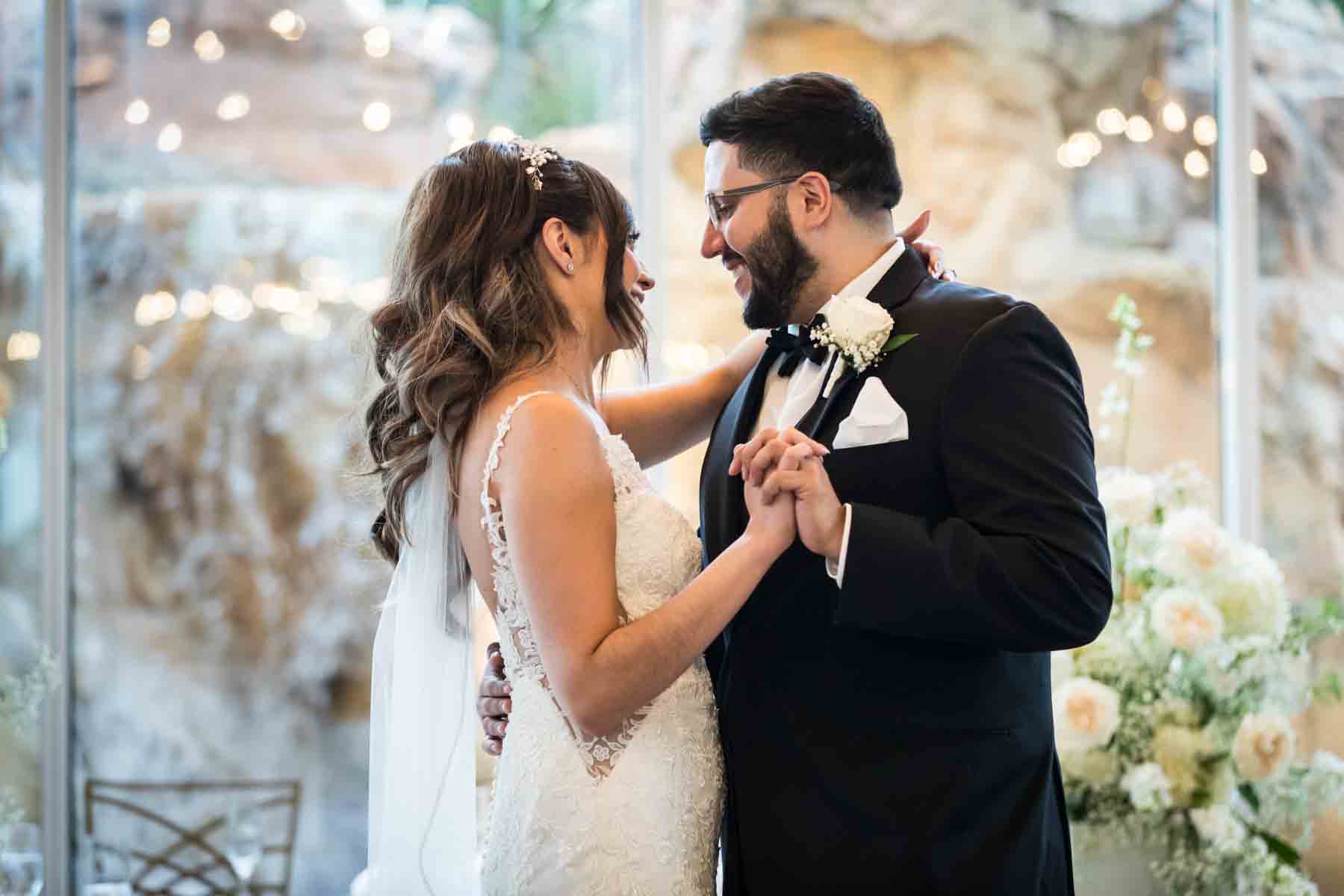 Old San Francisco wedding photos bride and groom dancing in front of glass wall and white flowers