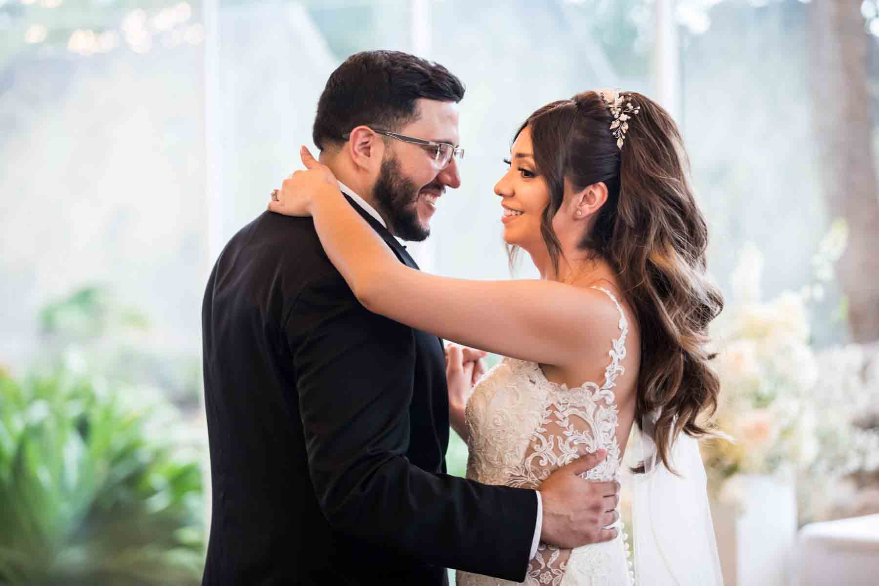 Old San Francisco wedding photos bride and groom dancing in front of glass wall and white flowers