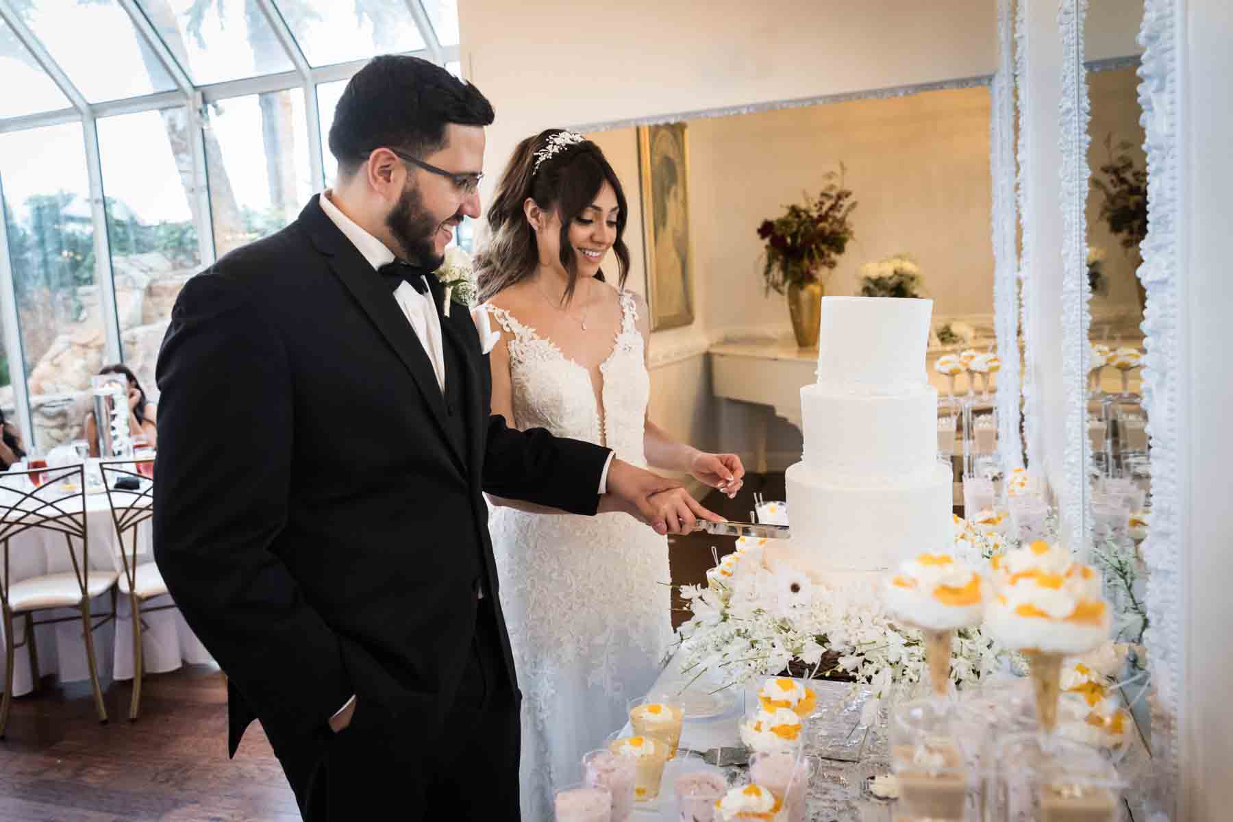 Bride and groom cutting wedding cake on table covered with desserts at an Old San Francisco Steakhouse wedding