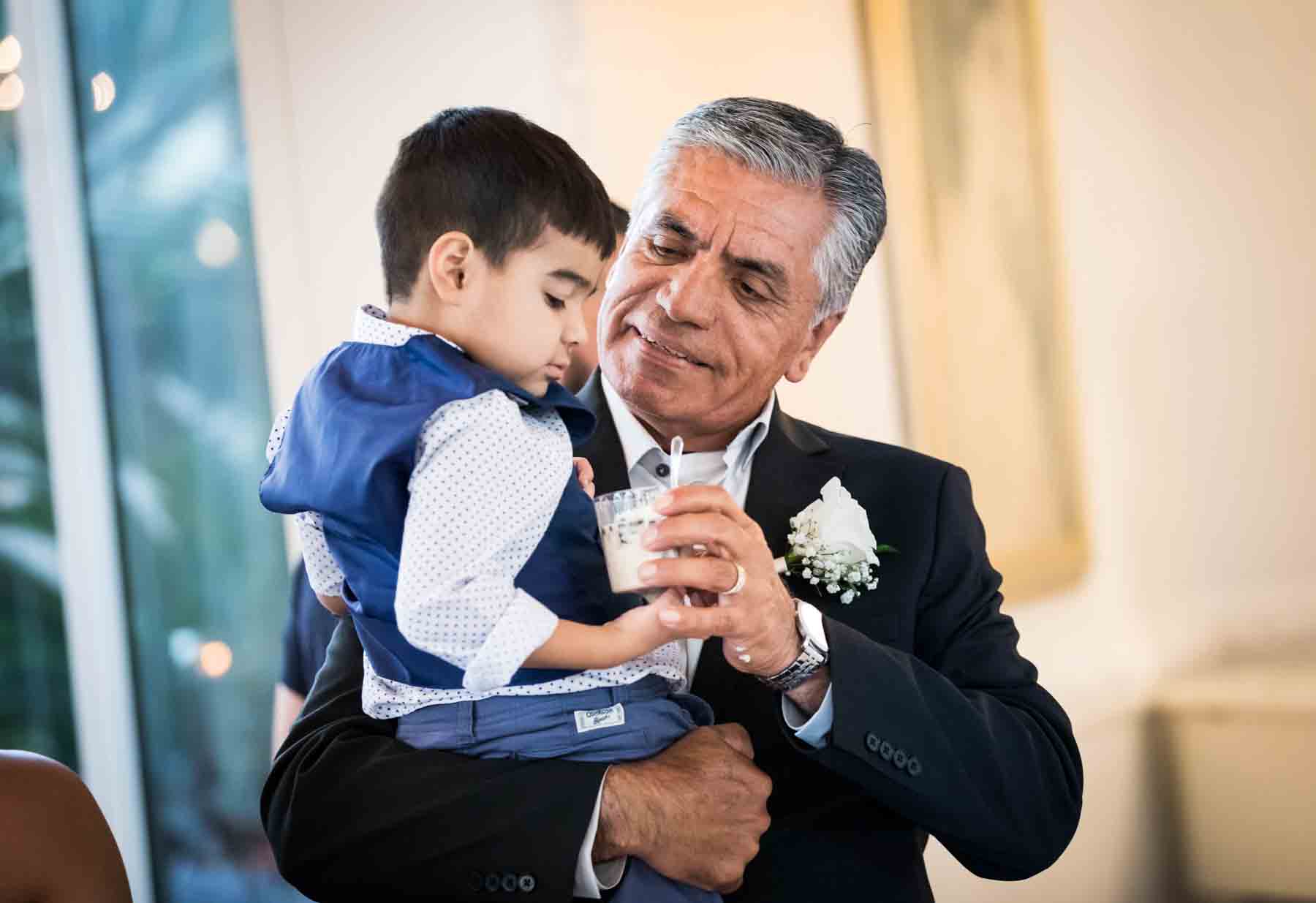 Older man giving cup of dessert to little boy in his arms at an Old San Francisco Steakhouse wedding