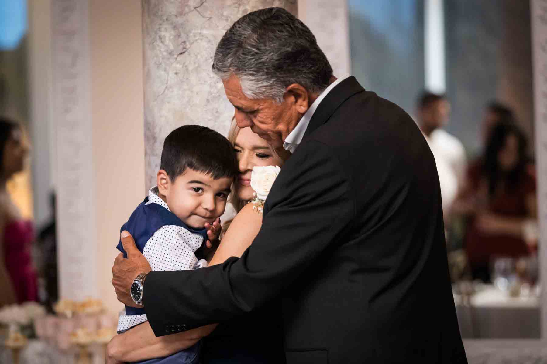 Grandparents holding little boy in front of column at an Old San Francisco Steakhouse wedding