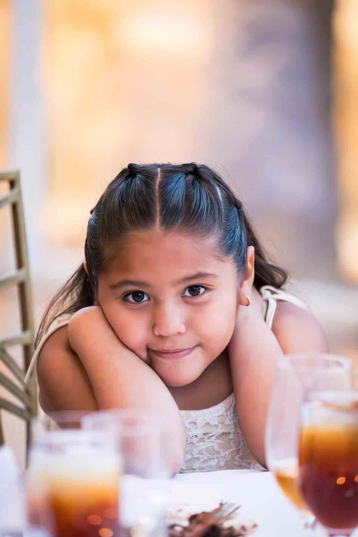 Little girl with hands around her neck sitting at table at an Old San Francisco Steakhouse wedding