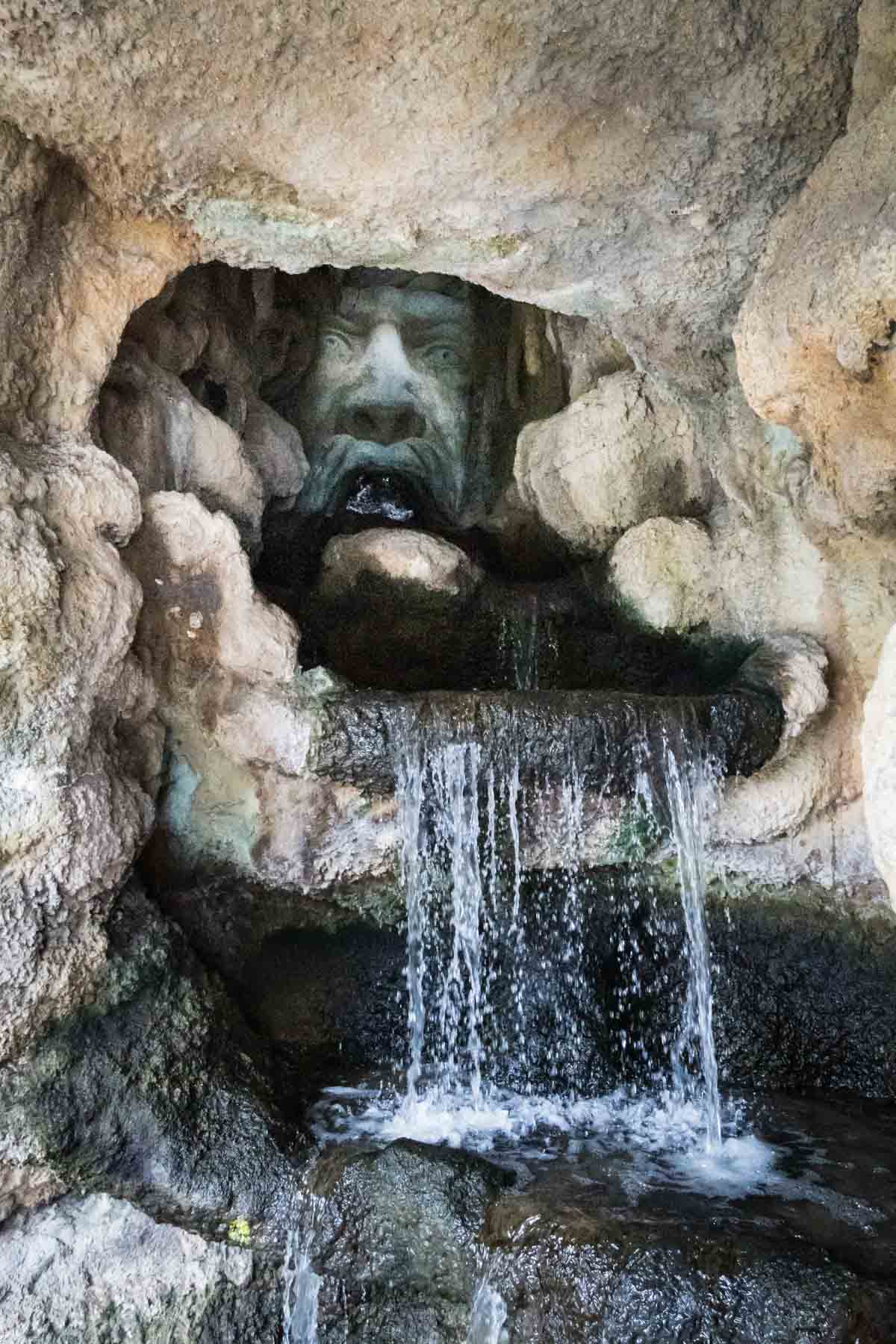 Ominous sculpture with waterfall in front at the Grotto on the River Walk