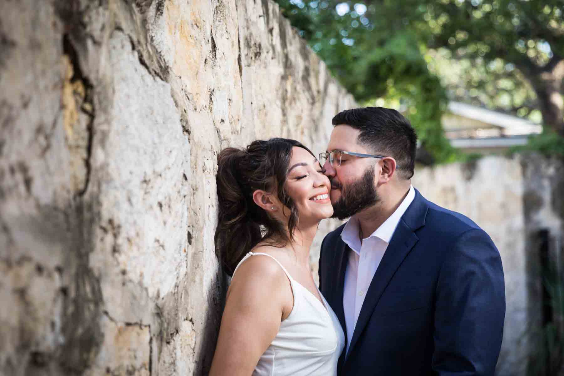 Couple kissing along stone wall at La Villita