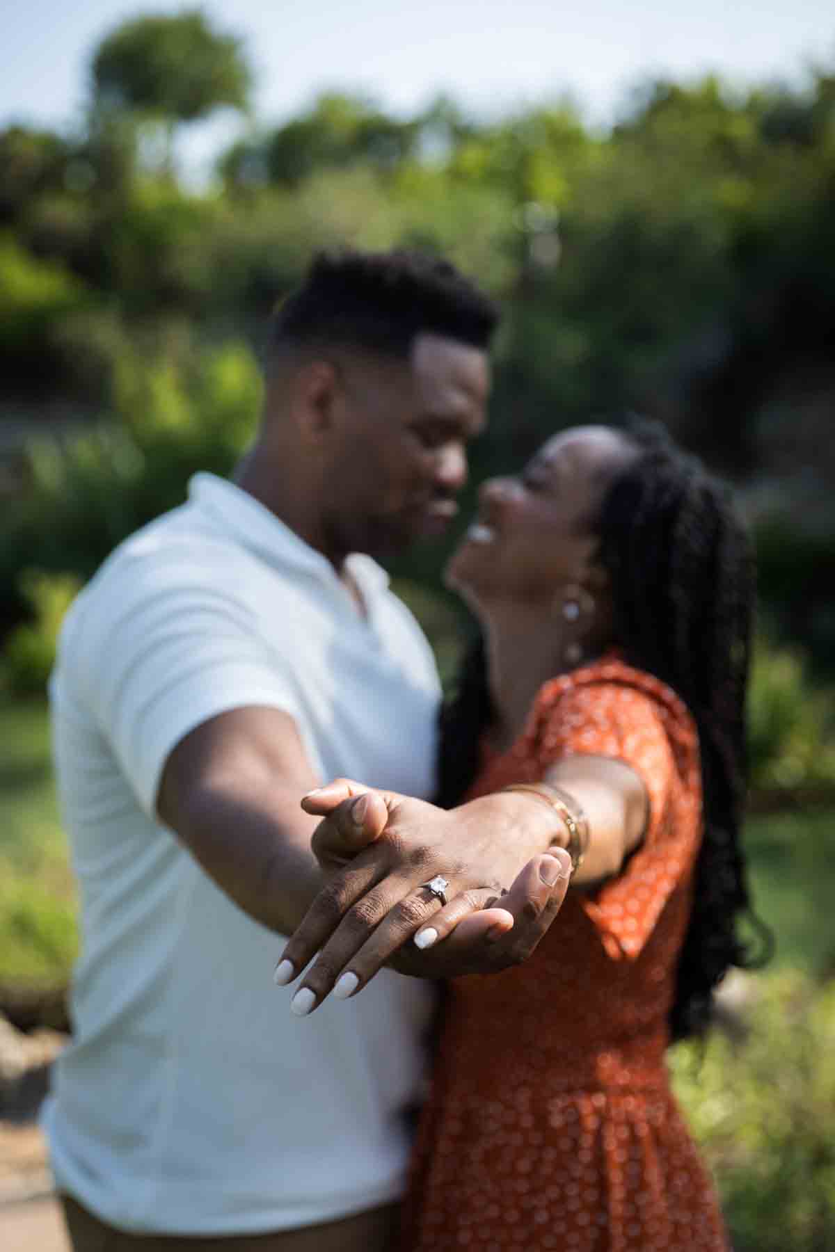 African American couple hugging with arms outstretched showing engagement ring at the Japanese Tea Garden for an article listing the best places to propose in San Antonio