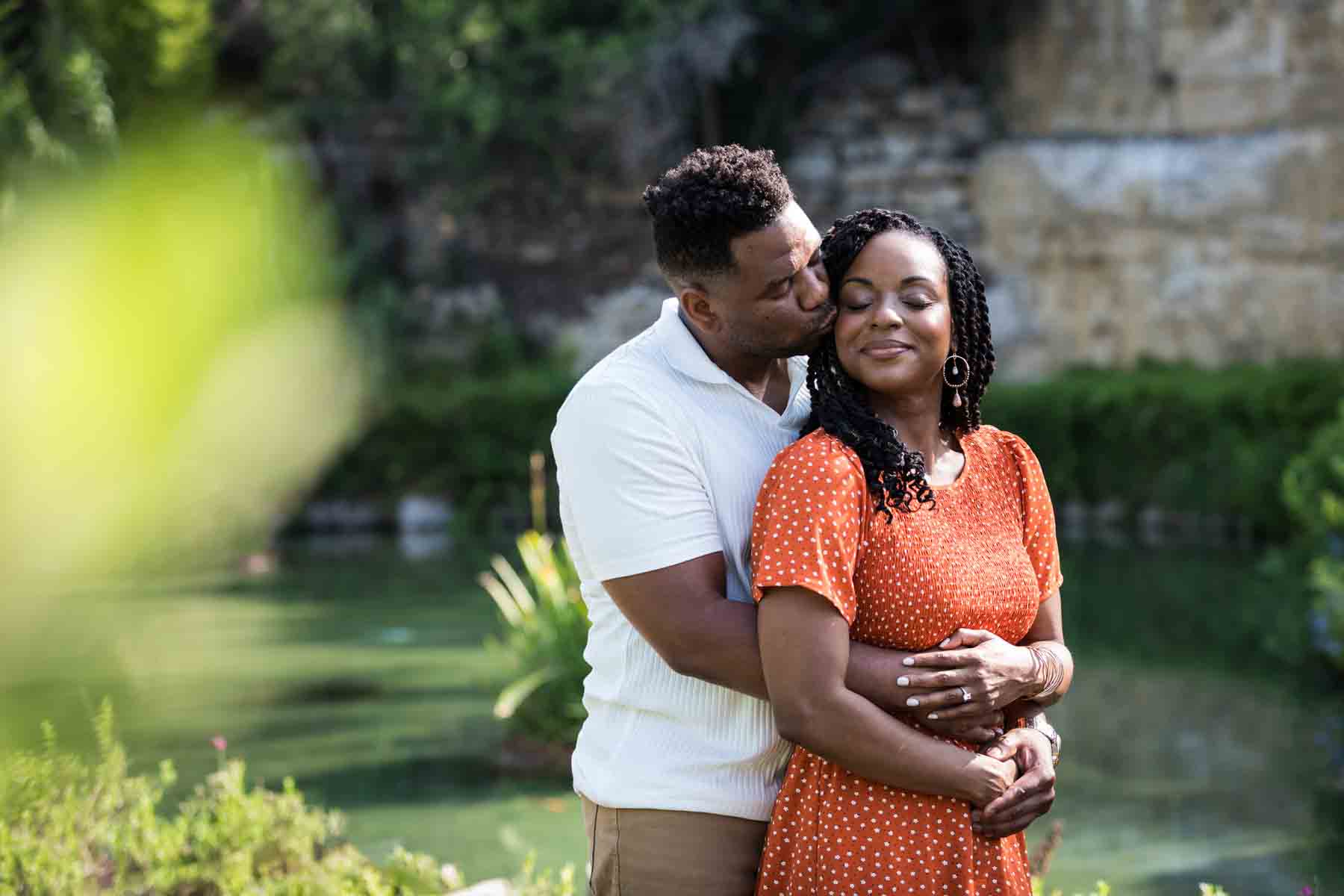 African American couple hugging in front of pond and green plants at the Japanese Tea Garden for an article listing the best places to propose in San Antonio