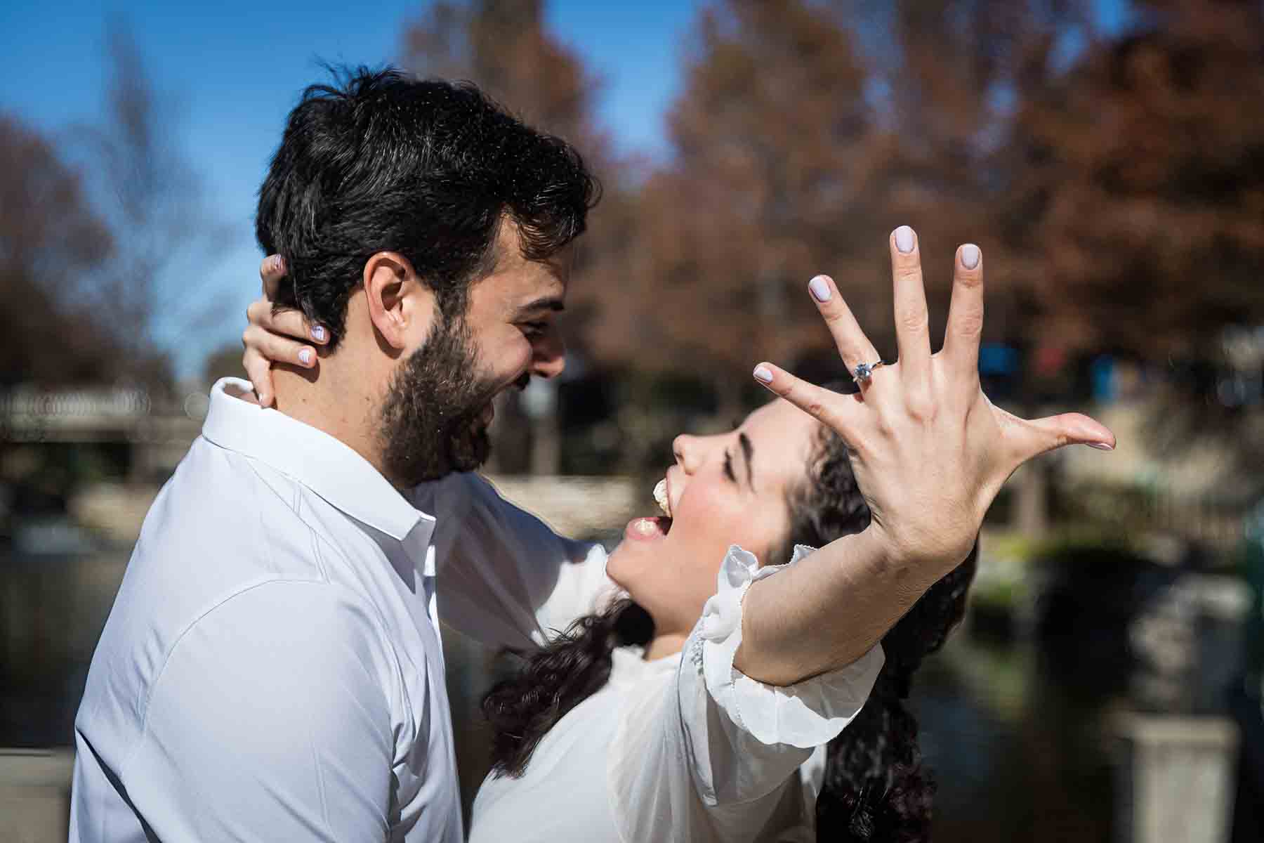 Man and woman hugging with woman holding out hand showing engagement ring for an article listing the best places to propose in San Antonio