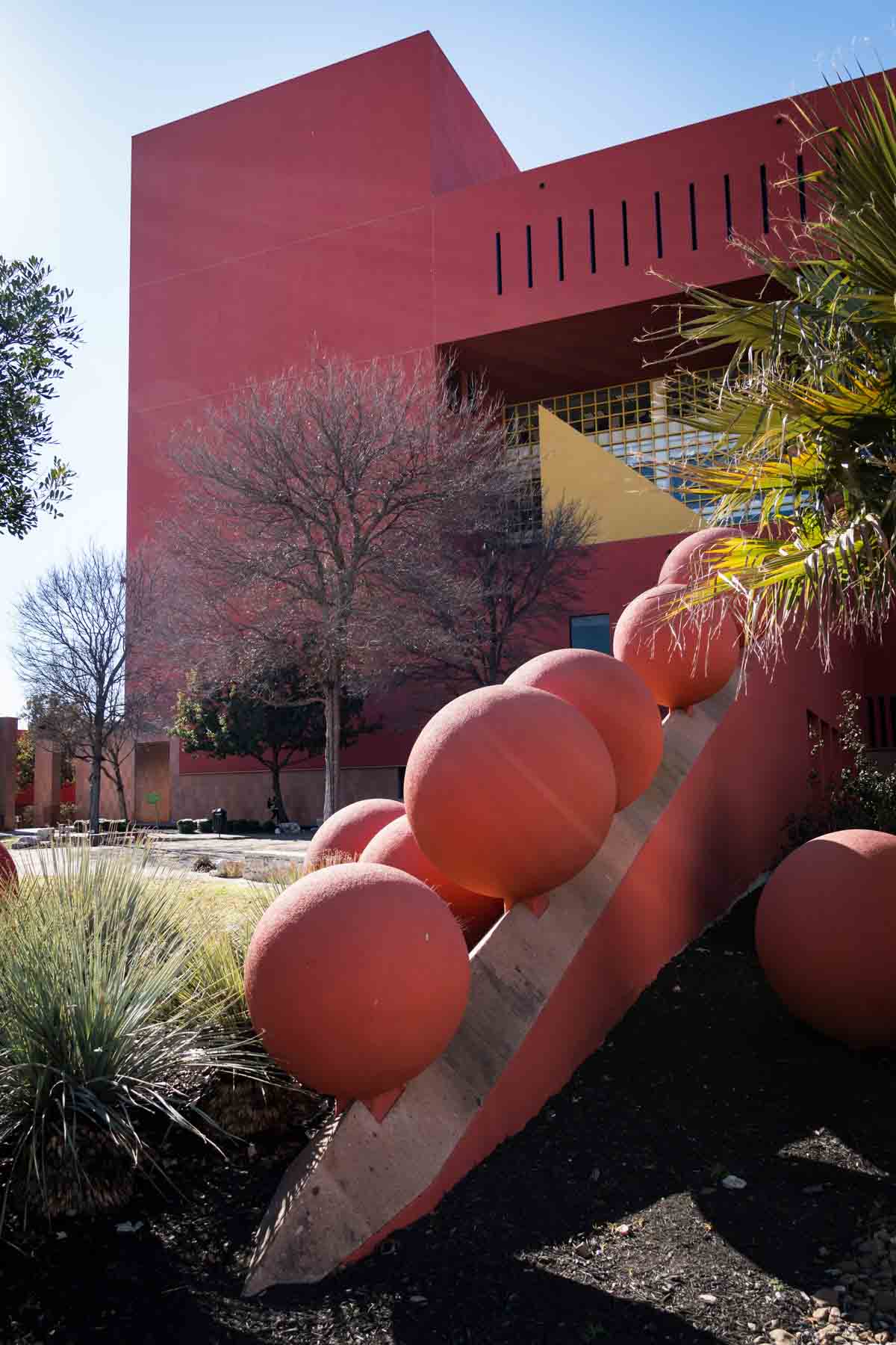 Central Library red building with round sculptures in front for an article listing the best places to propose in San Antonio