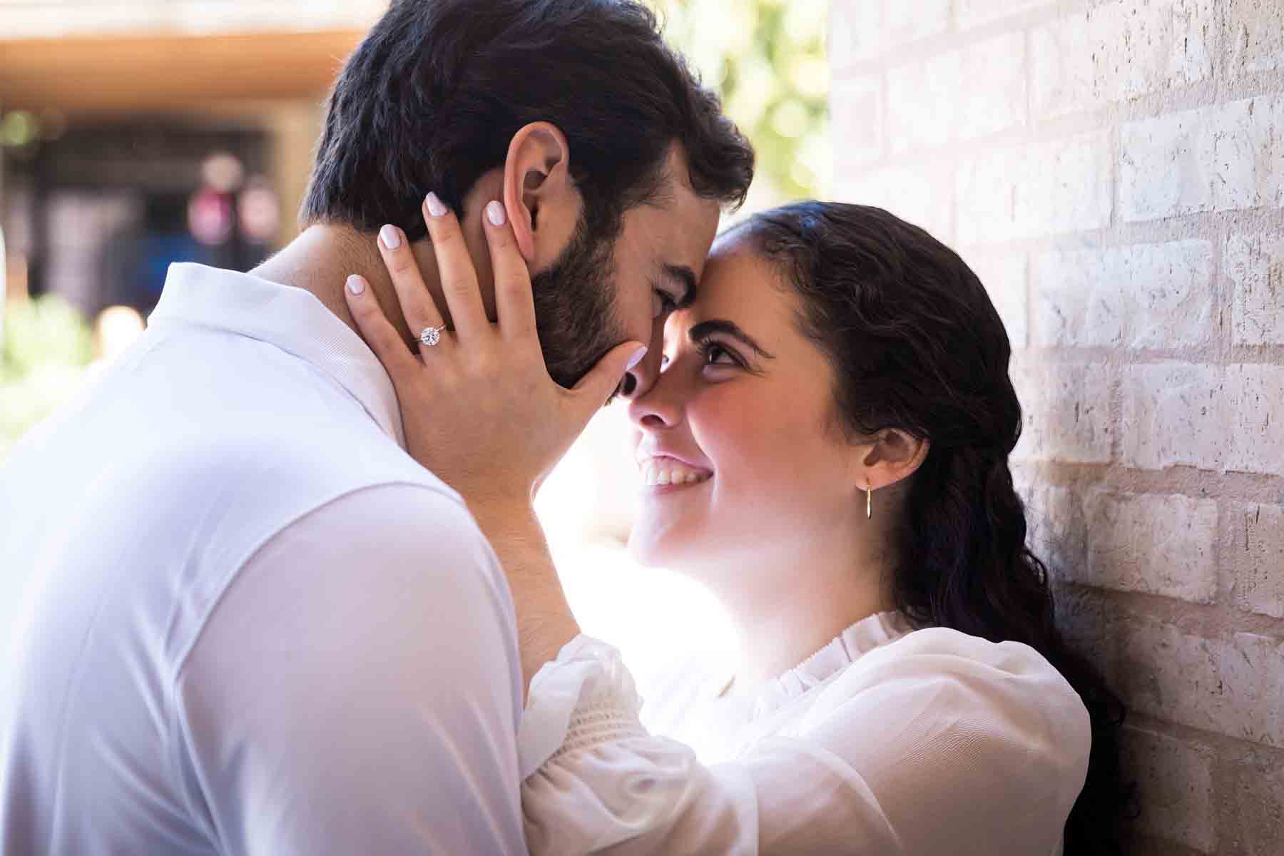 Man and woman hugging with woman's hand on man's face showing engagement ring for an article listing the best places to propose in San Antonio