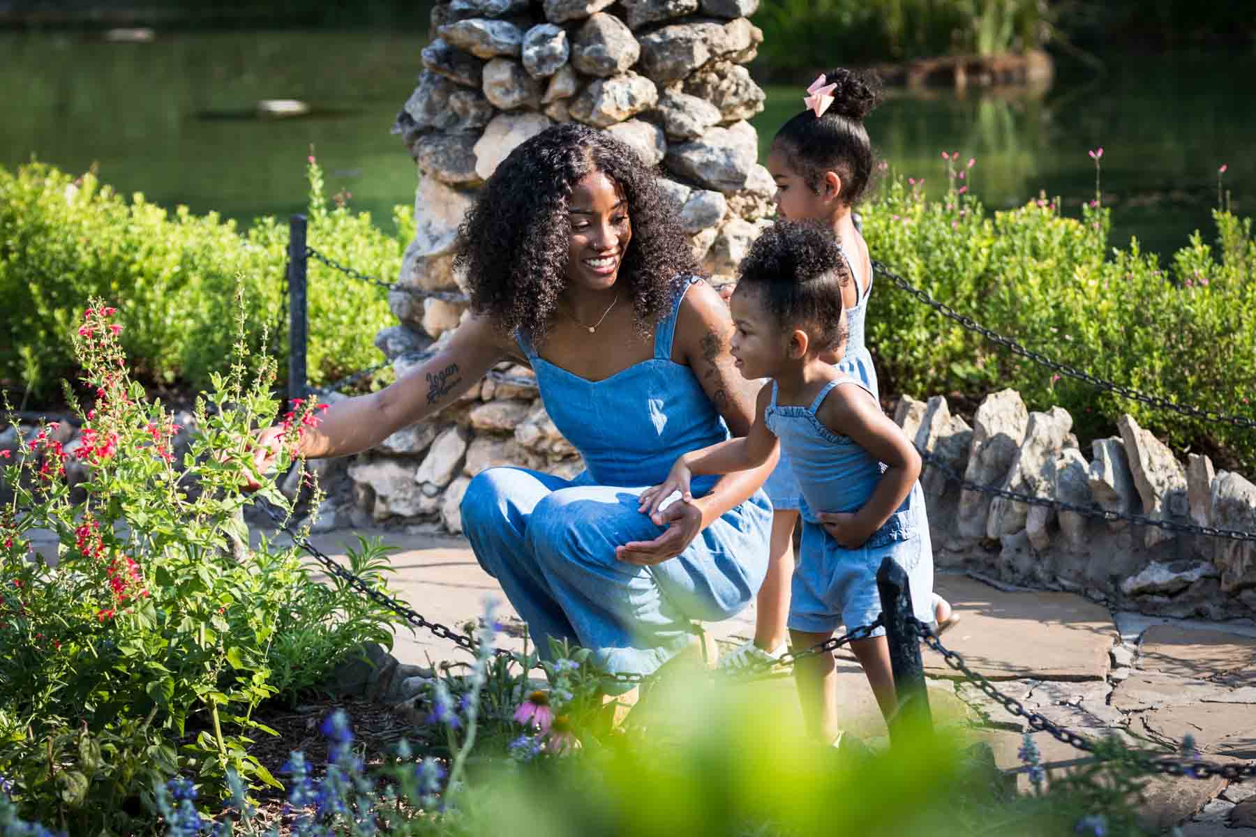 African American mother showing flowers to her two adorable daughters in the pathway of the Japanese Tea Garden in front of a pond for an article on 'How often should I take family photos?'