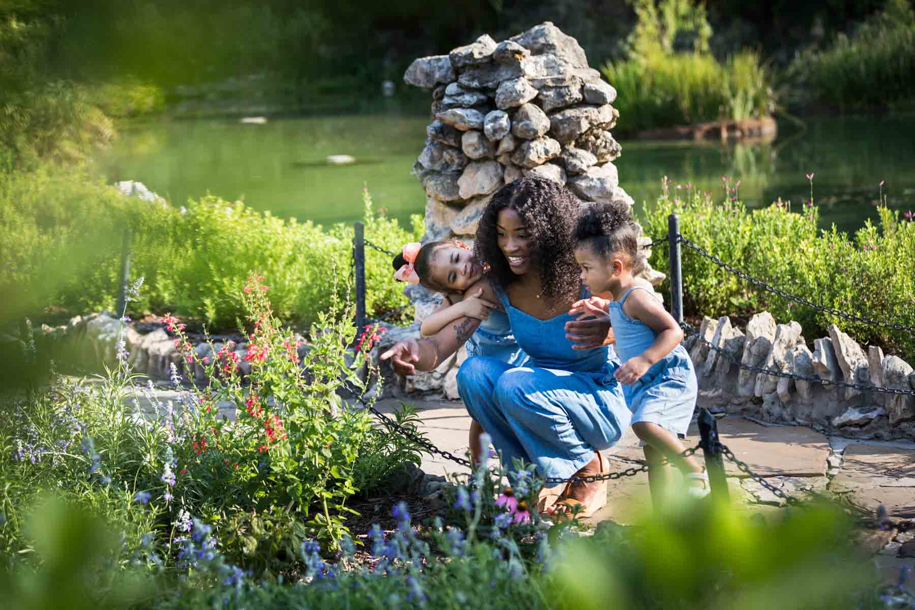 African American mother showing flowers to her two adorable daughters in the pathway of the Japanese Tea Garden in front of a pond for an article on 'How often should I take family photos?'