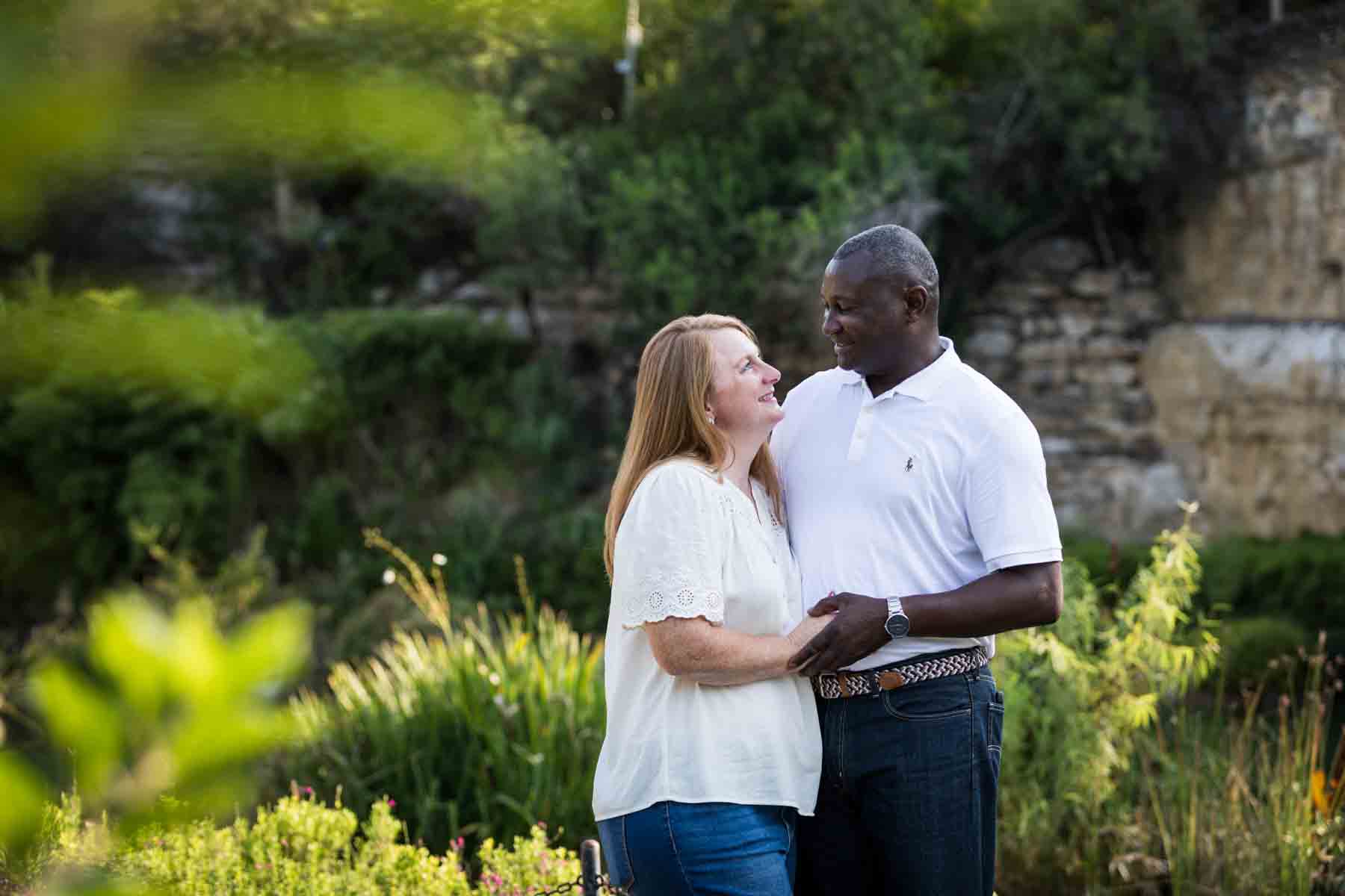 Mixed race couple smiling at each other in front of plants and stone wall at the Japanese Tea Garden for an article on 'How often should I take family photos?'