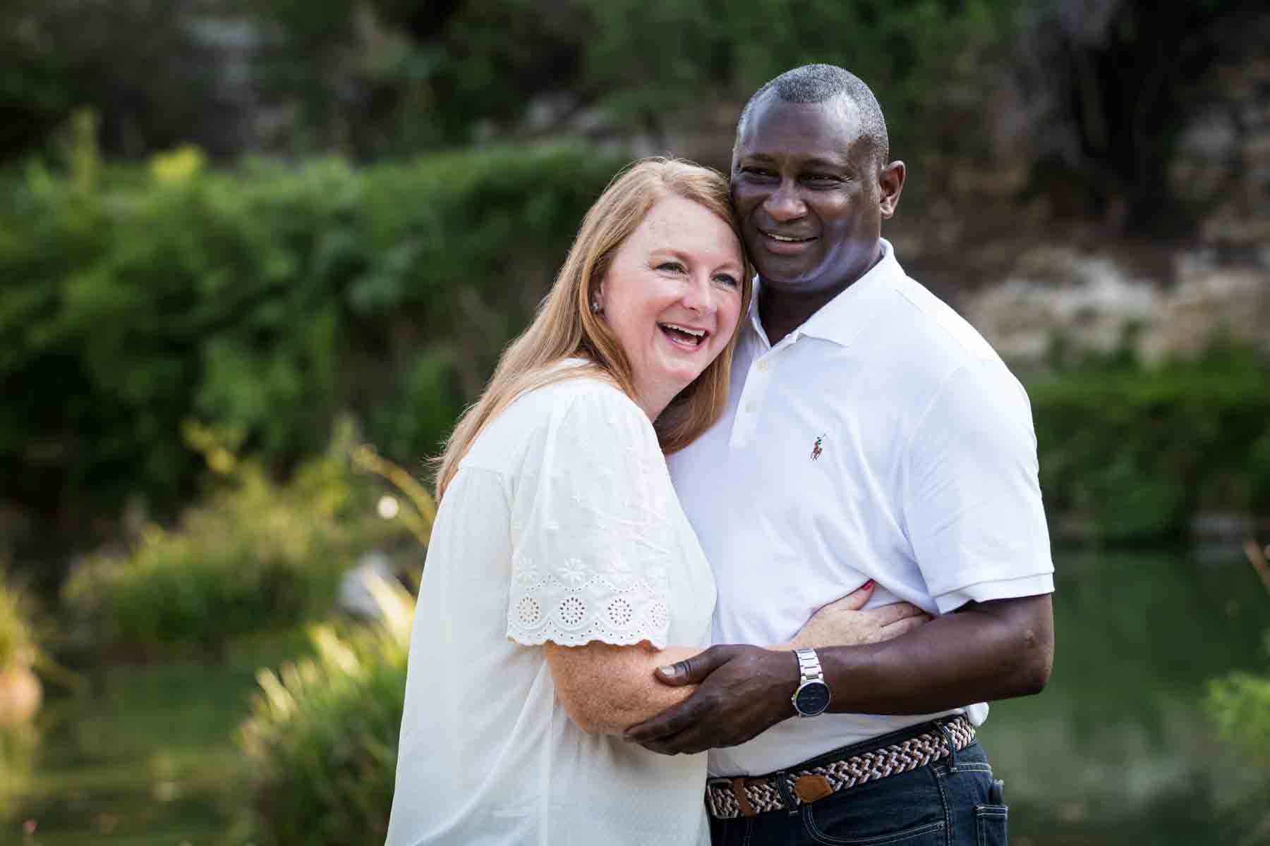 Mixed race couple hugging each other in front of plants and stone wall at the Japanese Tea Garden for an article on 'How often should I take family photos?'