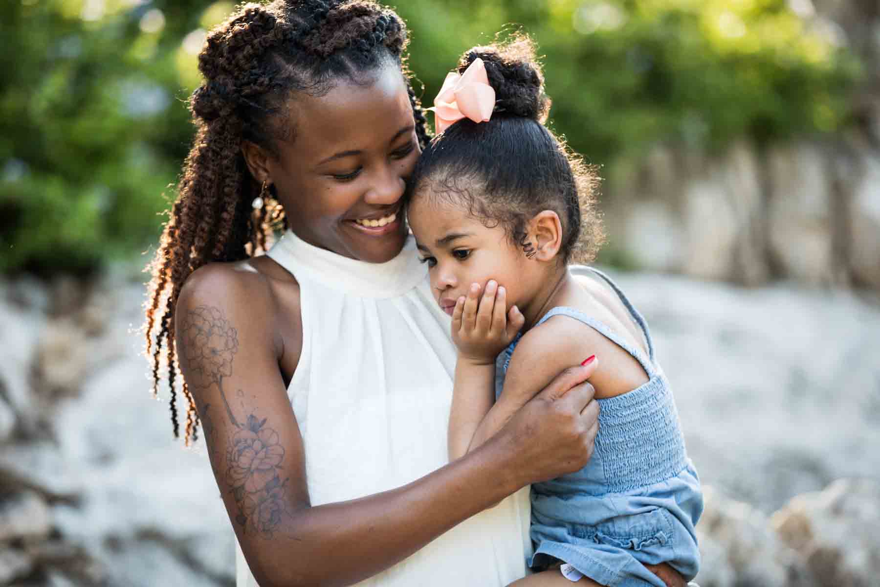 Beautiful African American woman wearing white sleeveless top holding little girl and smiling in Japanese Tea Garden