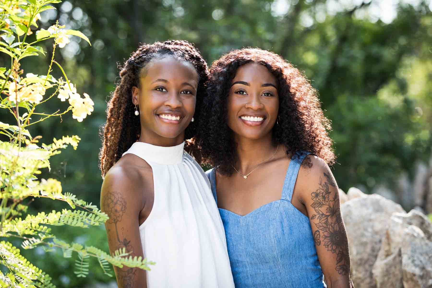 Two African American sisters wearing blue and white standing in the Japanese Tea Garden in front of a bush for an article on 'How often should I take family photos?'