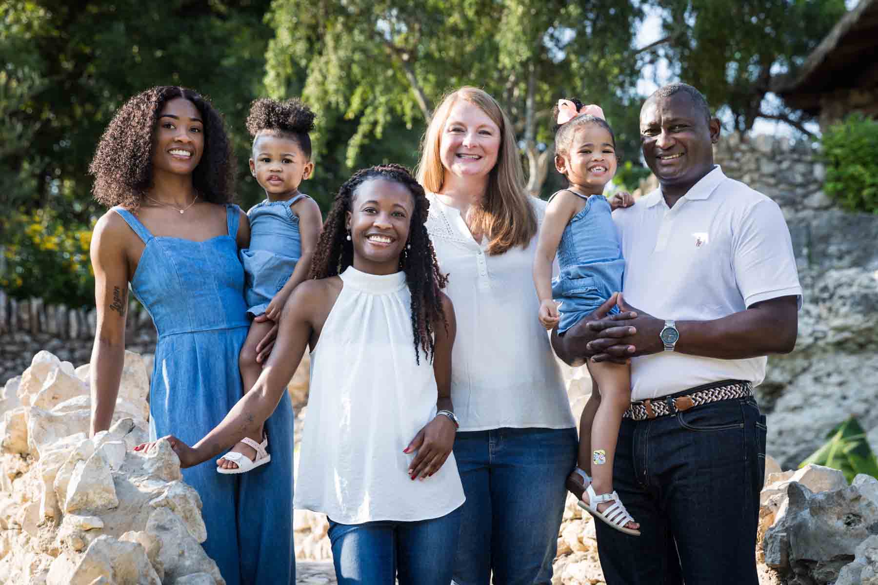 Mixed race family holding two adorable little girls in front of stone wall at the Japanese Tea Garden for an article on 'How often should I take family photos?'