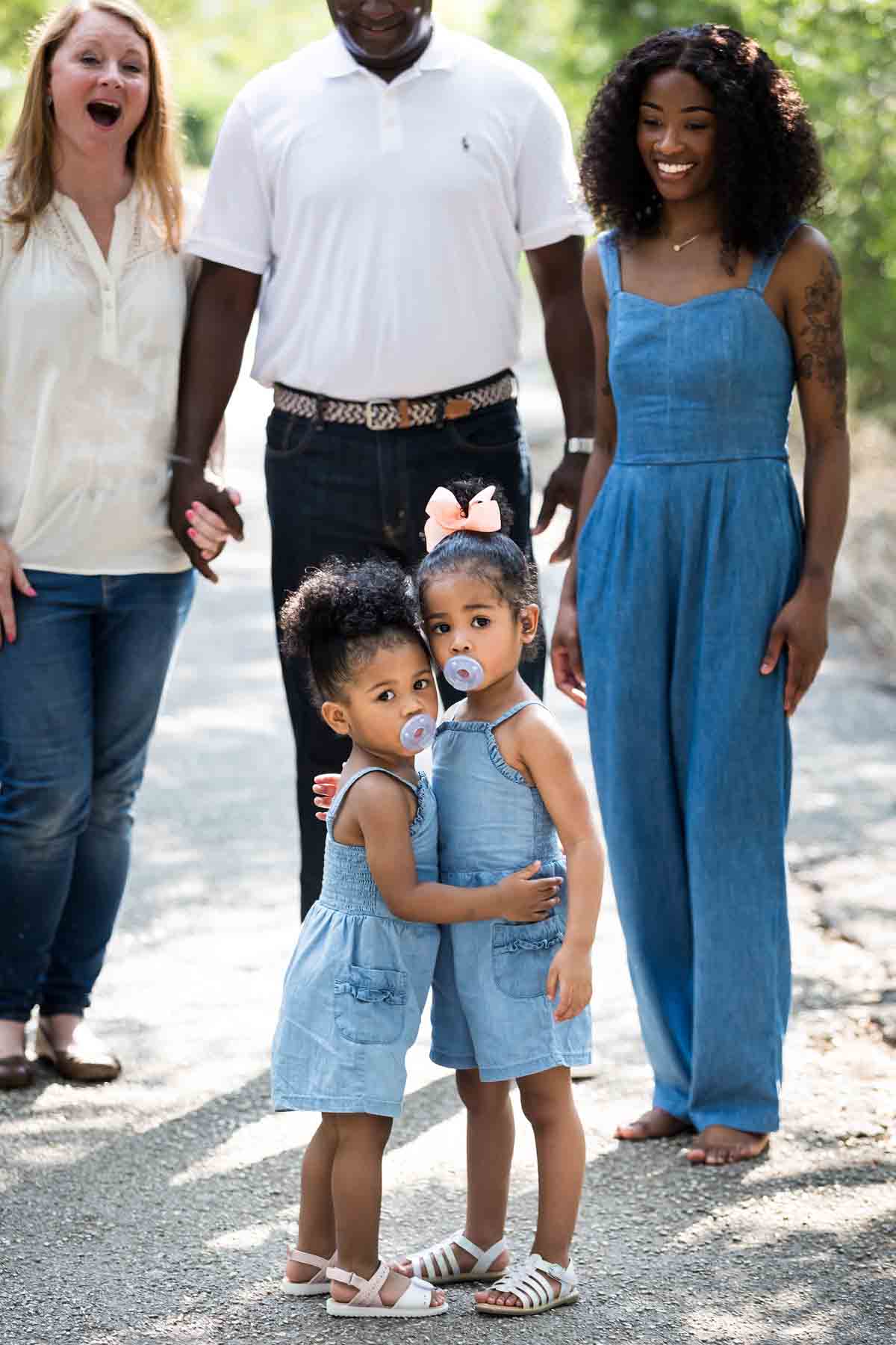 wo adorable little girls hugging each other in front of family in forest of Brackenridge Park