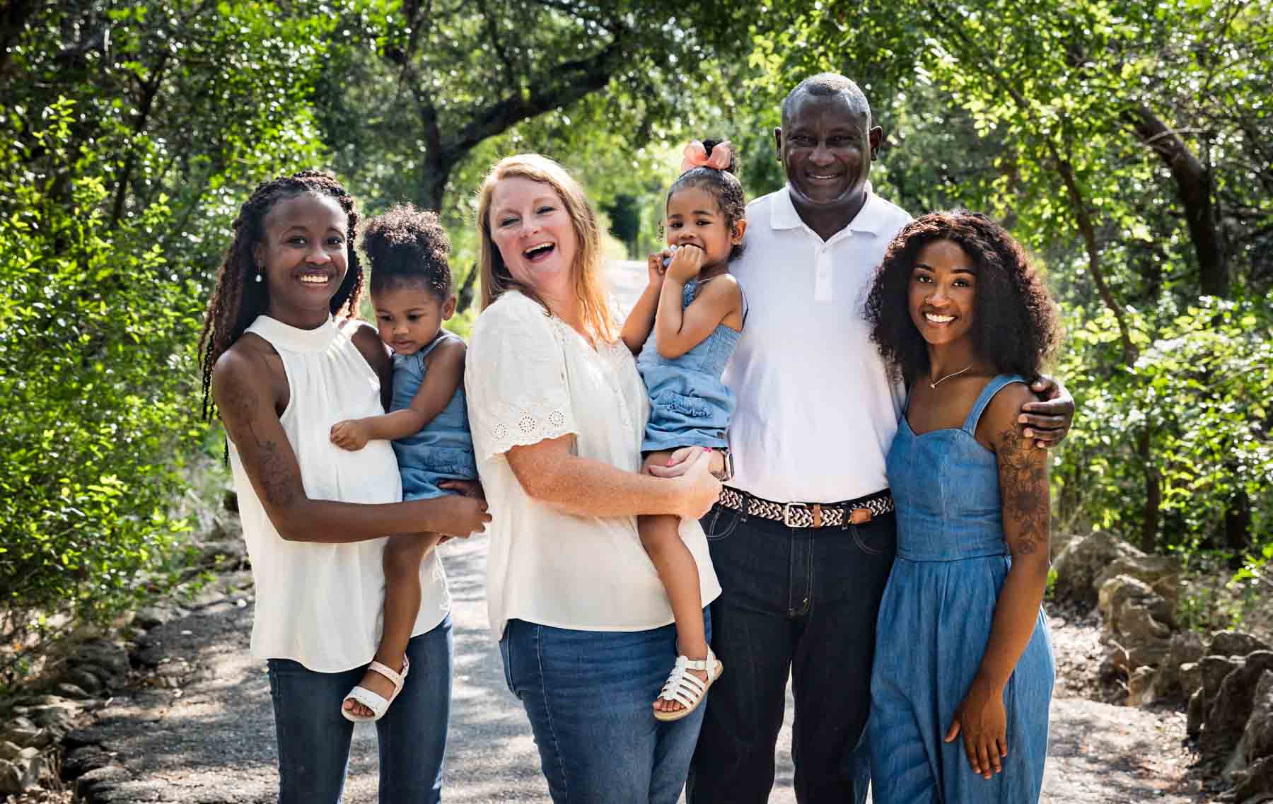 Mixed race family including grandparents, two daughters and two granddaughters in Brackenridge Park forest