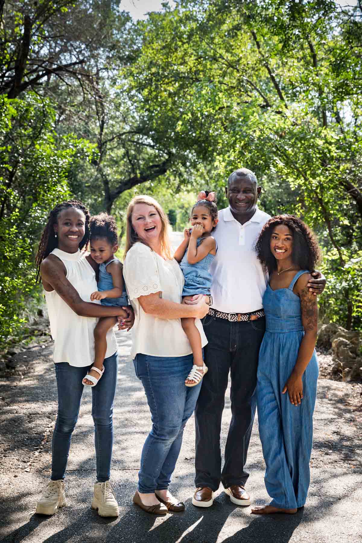 Mixed race family including grandparents, two daughters and two granddaughters in Brackenridge Park forest