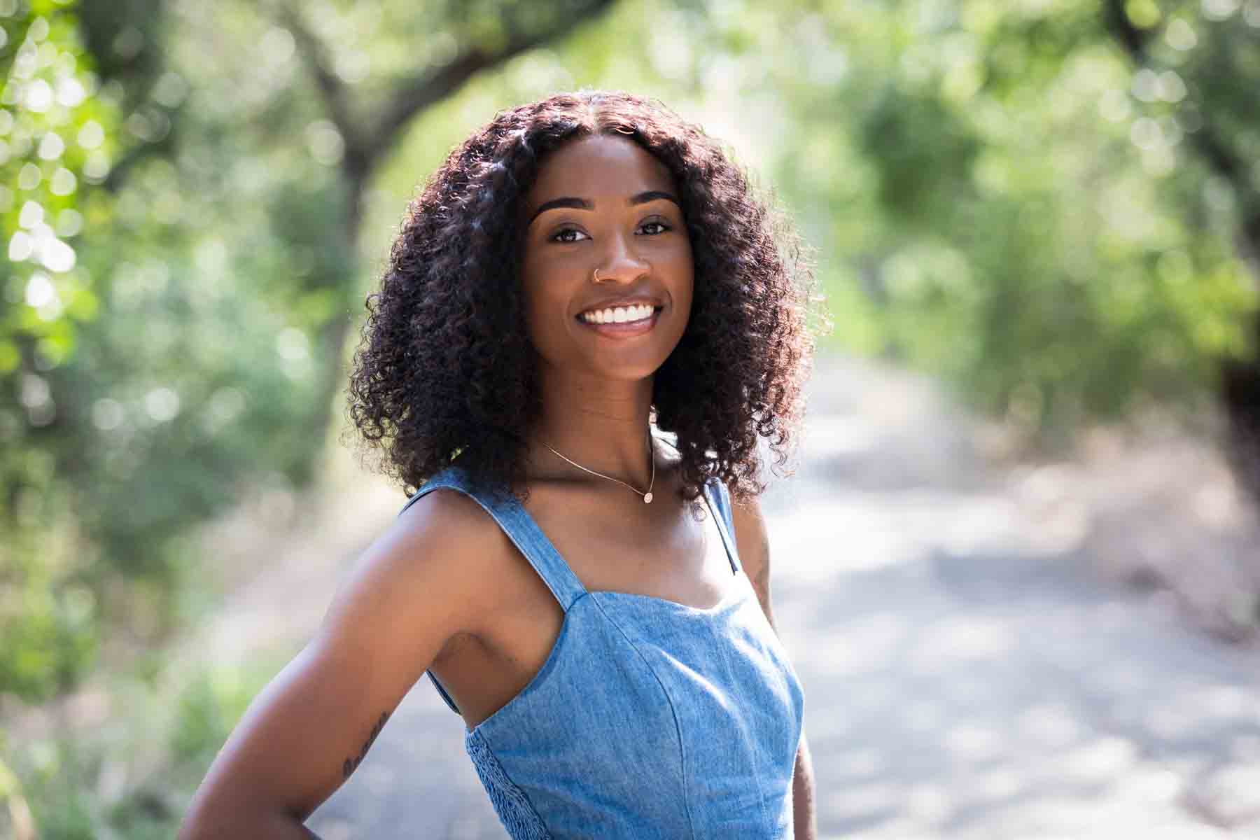 Beautiful African American woman wearing denim jumper in pathway of Brackenridge Park