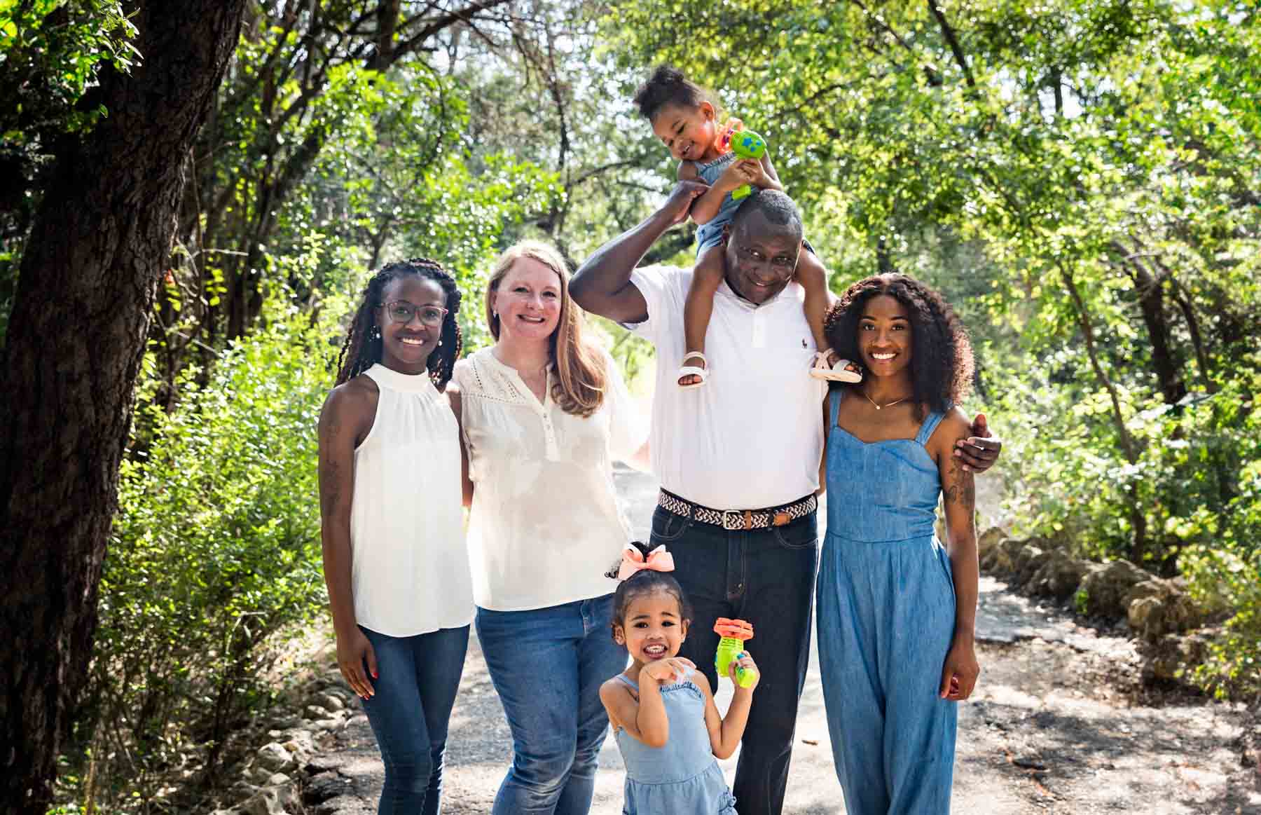 Mixed race family including grandparents, two daughters and two granddaughters in Brackenridge Park forest