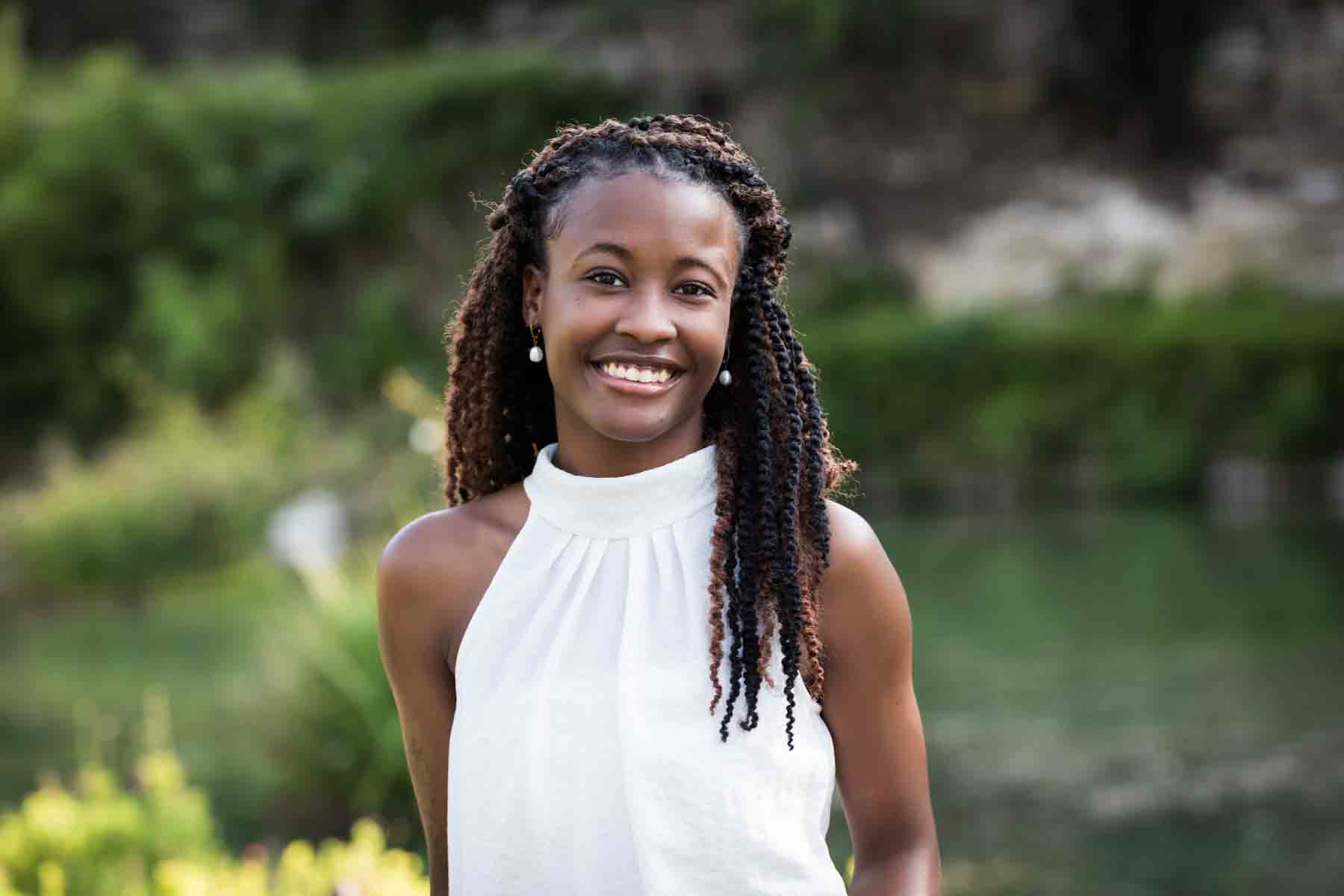 Beautiful African American woman with braids wearing white sleeveless shirt in front of plants at the Japanese Tea Garden