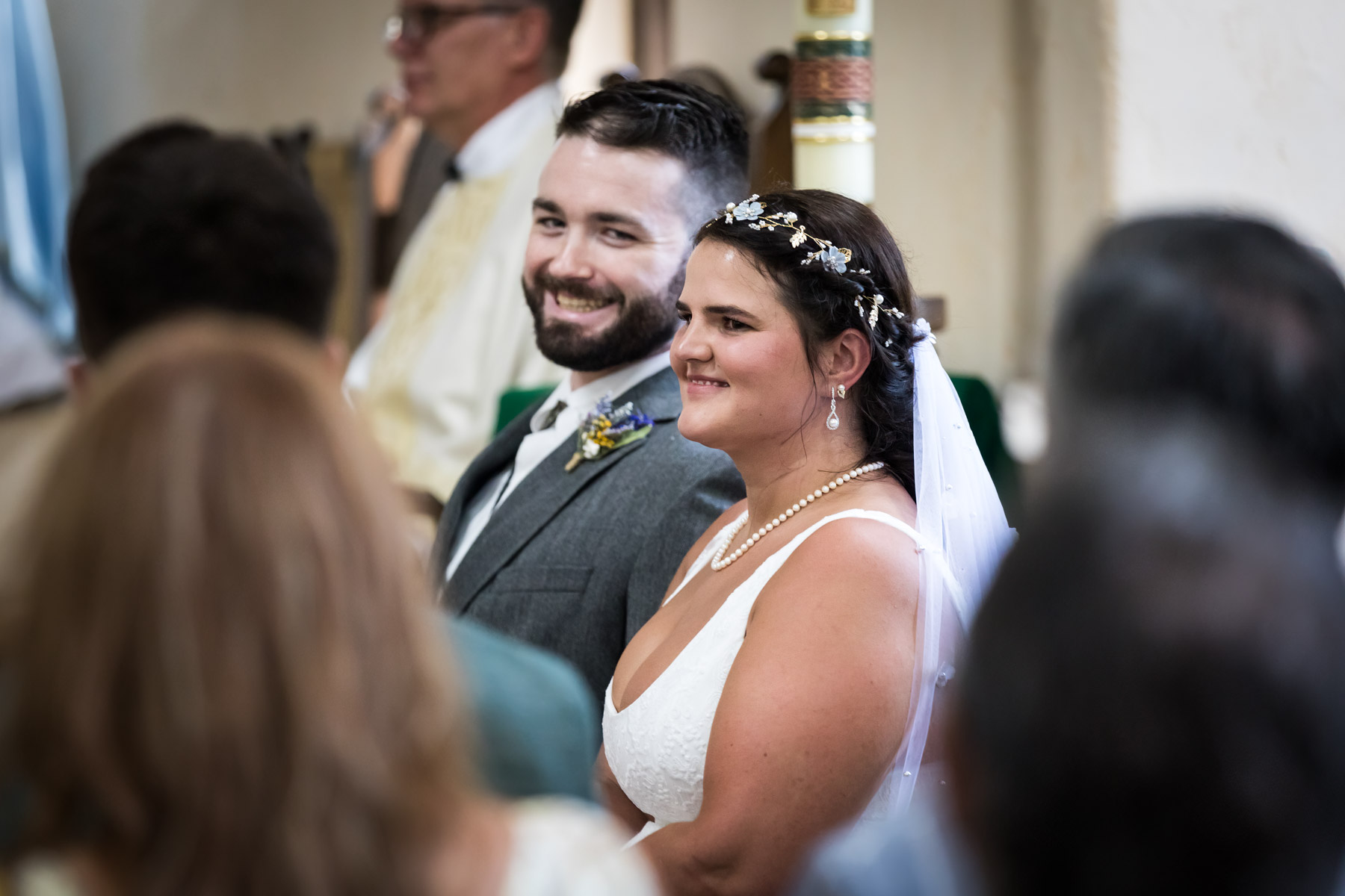 Bride and groom smiling during ceremony while seated for an article on how to get married at Mission Espada