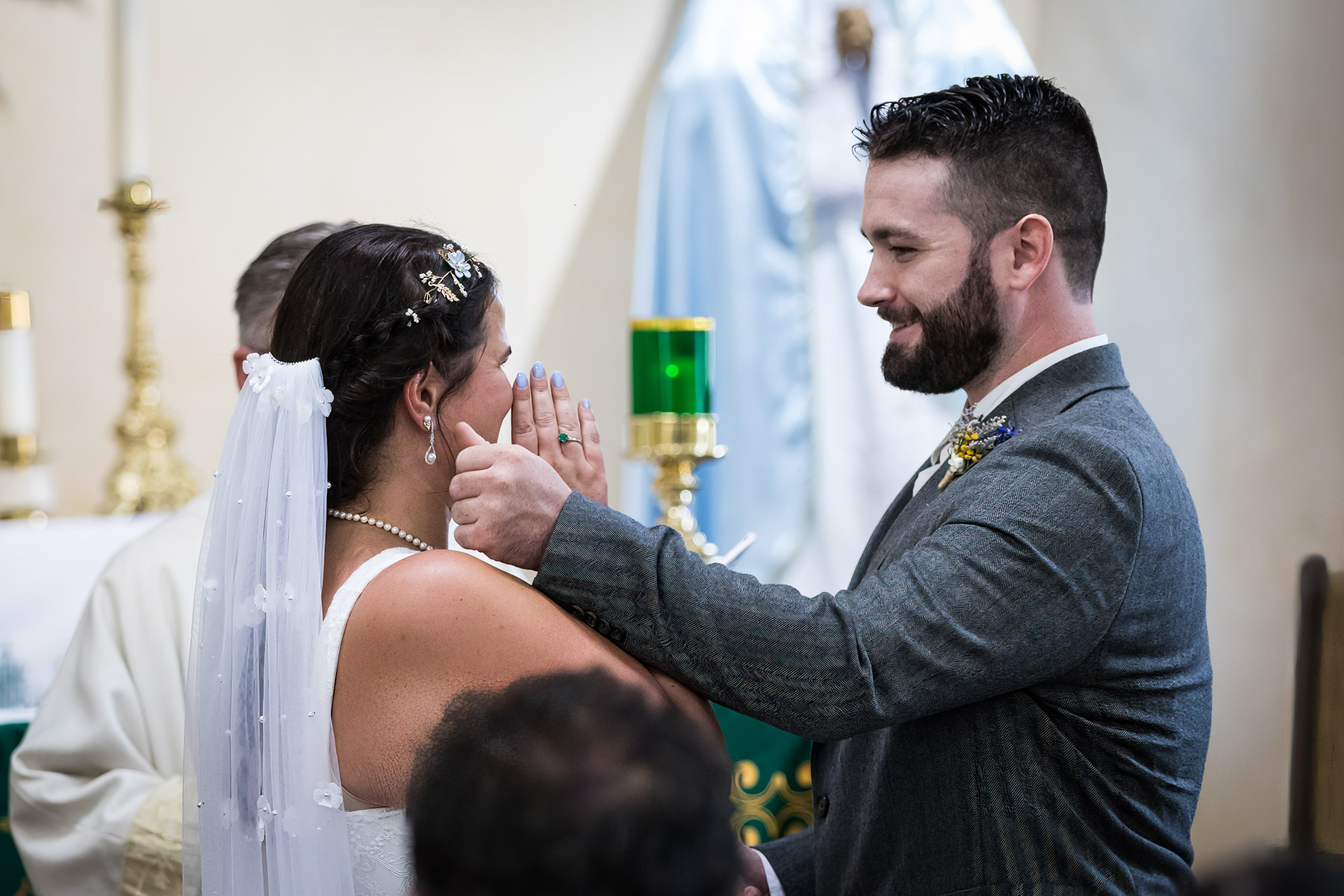 Groom wiping away tear from bride's cheek during ceremony for an article on how to get married at Mission Espada