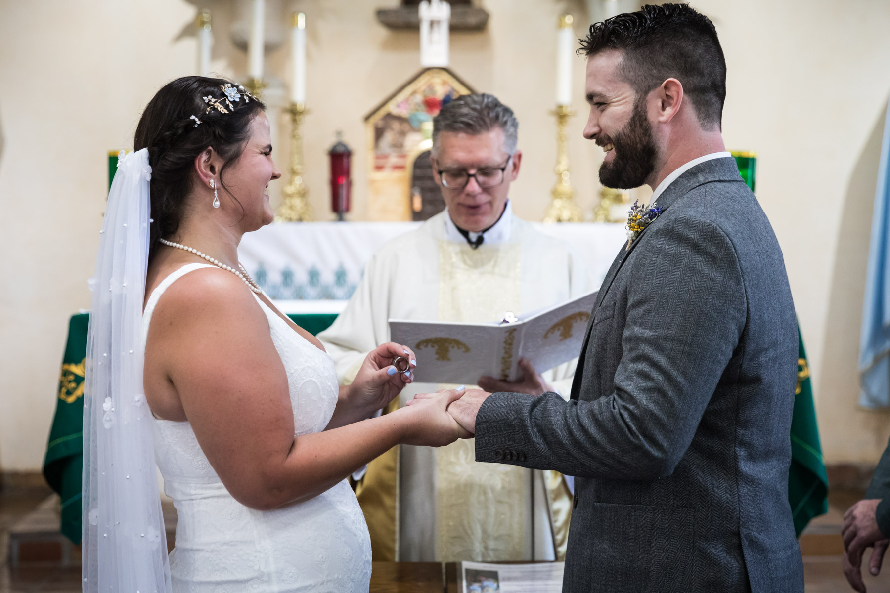 Bride about to put ring on groom's finger during ceremony for an article on how to get married at Mission Espada