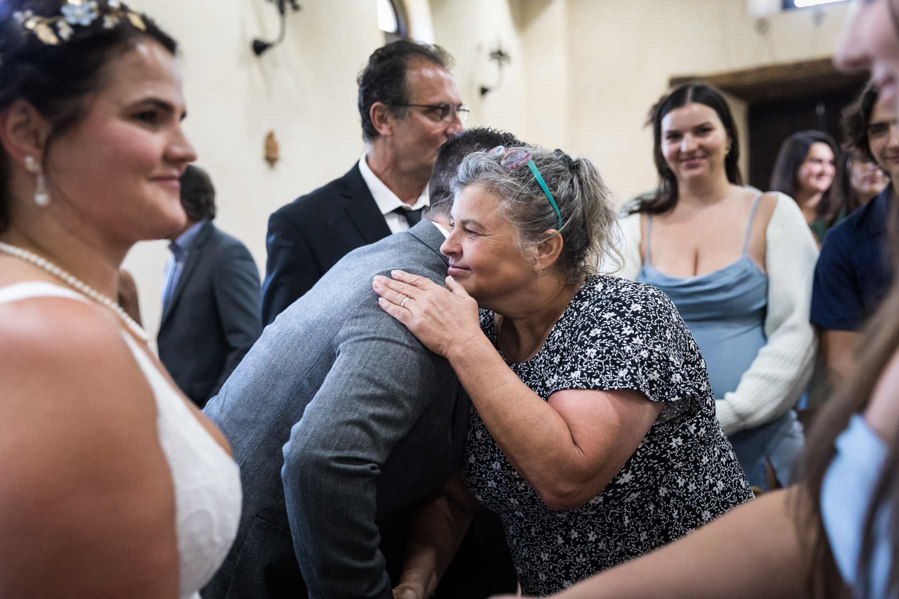 Mother and groom hugging in front of guests for an article on how to get married at Mission Espada