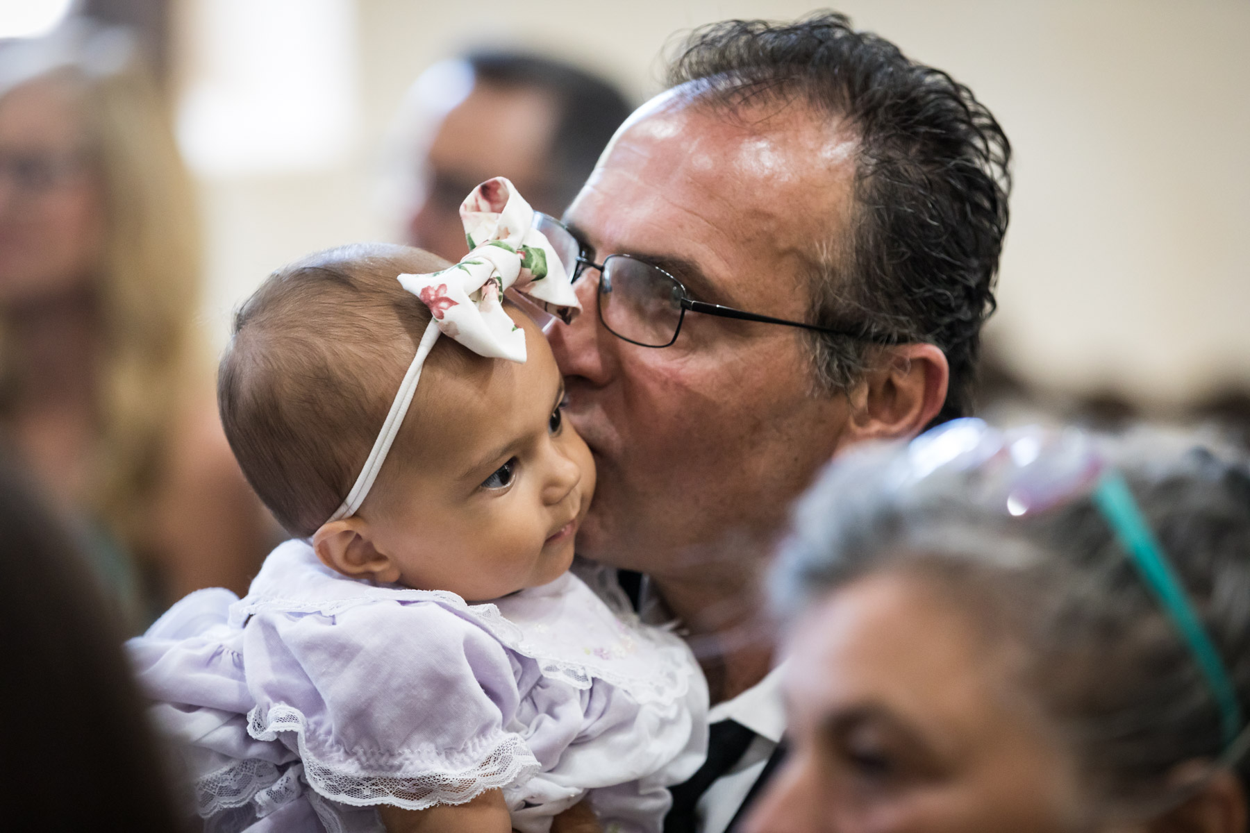 Grandfather kissing baby girl wearing bow on her head