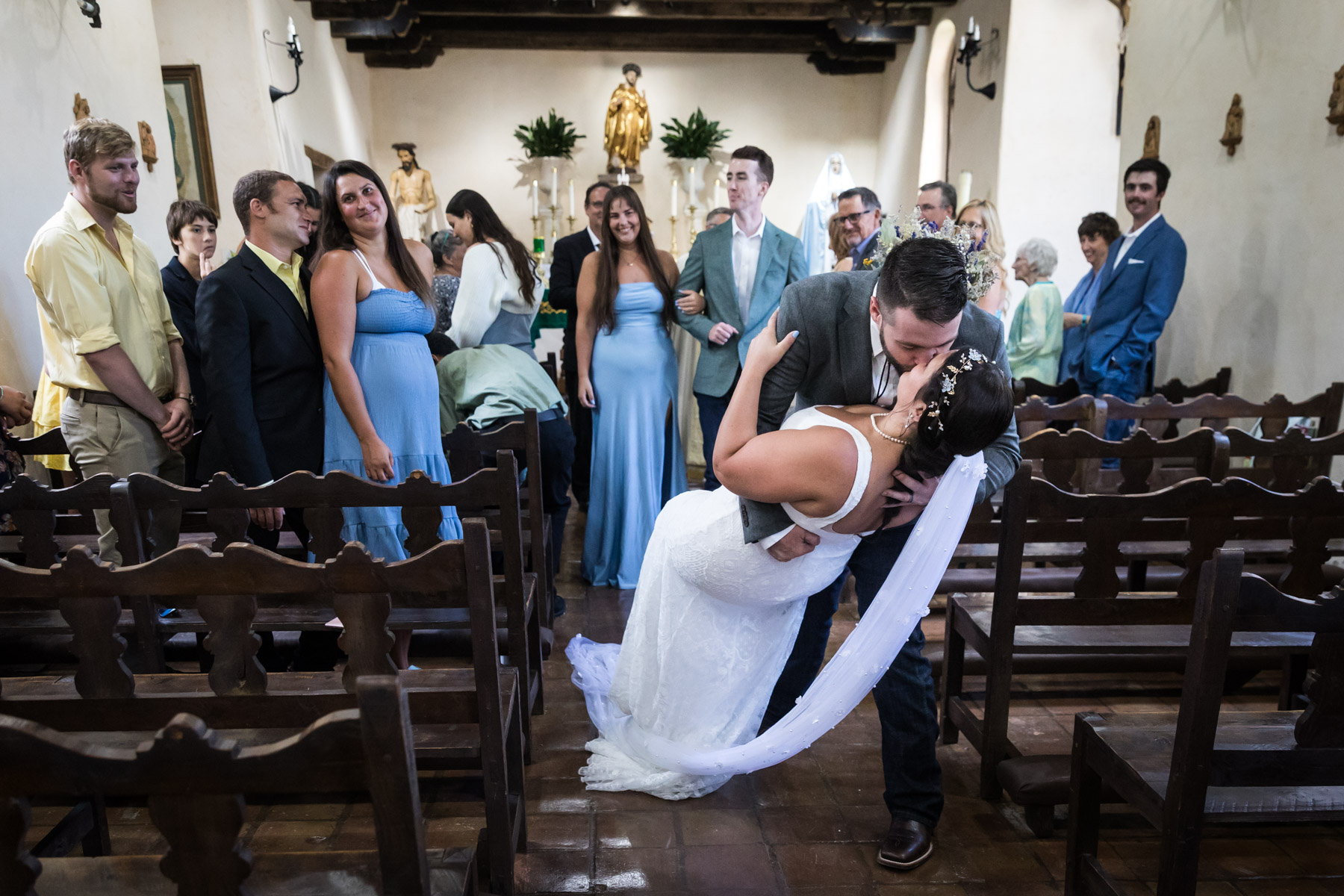 Dramatic kiss at end of aisle for bride and groom for an article on how to get married at Mission Espada