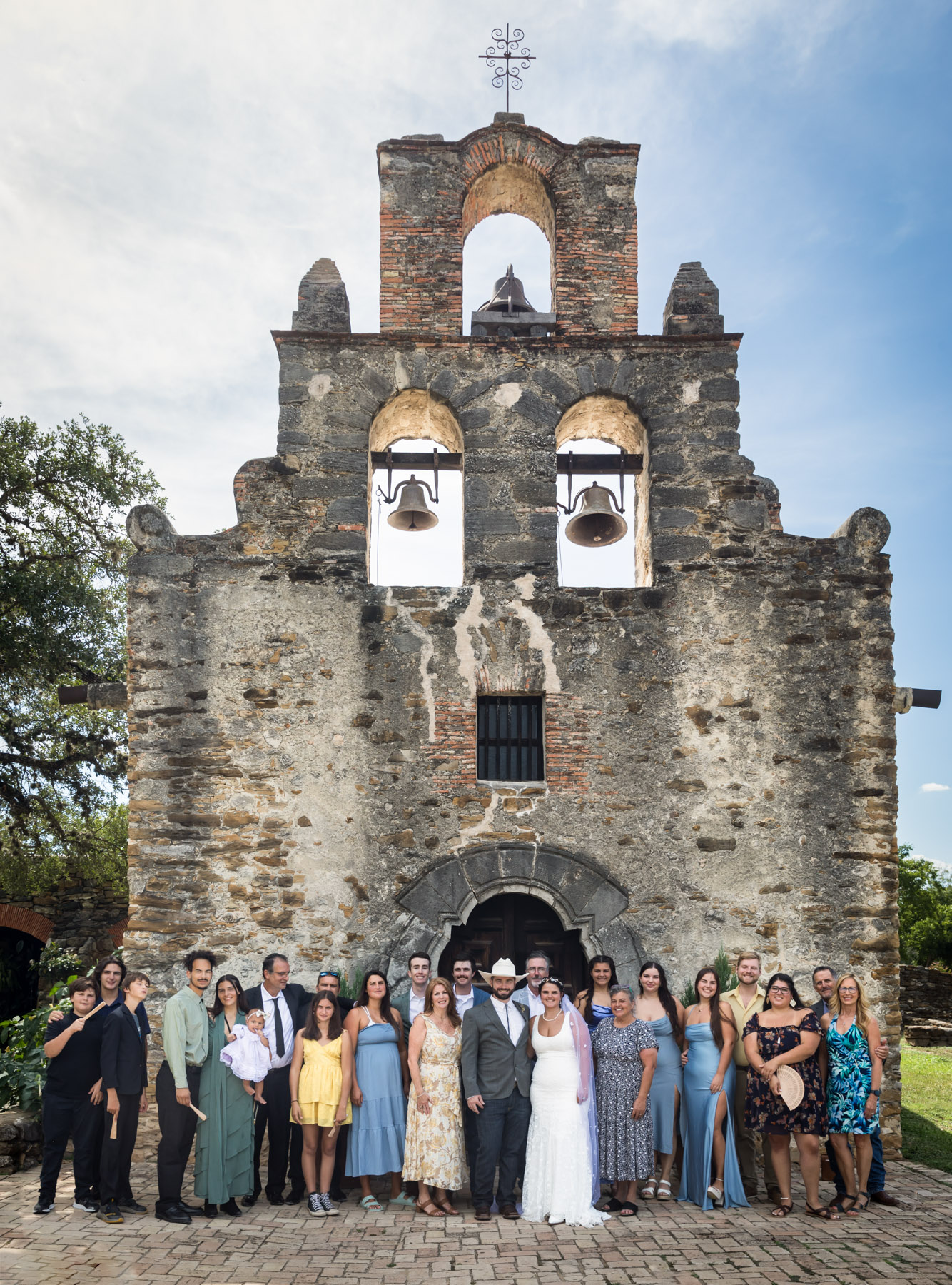 Large family photo in front of stone facade of Mission Espada