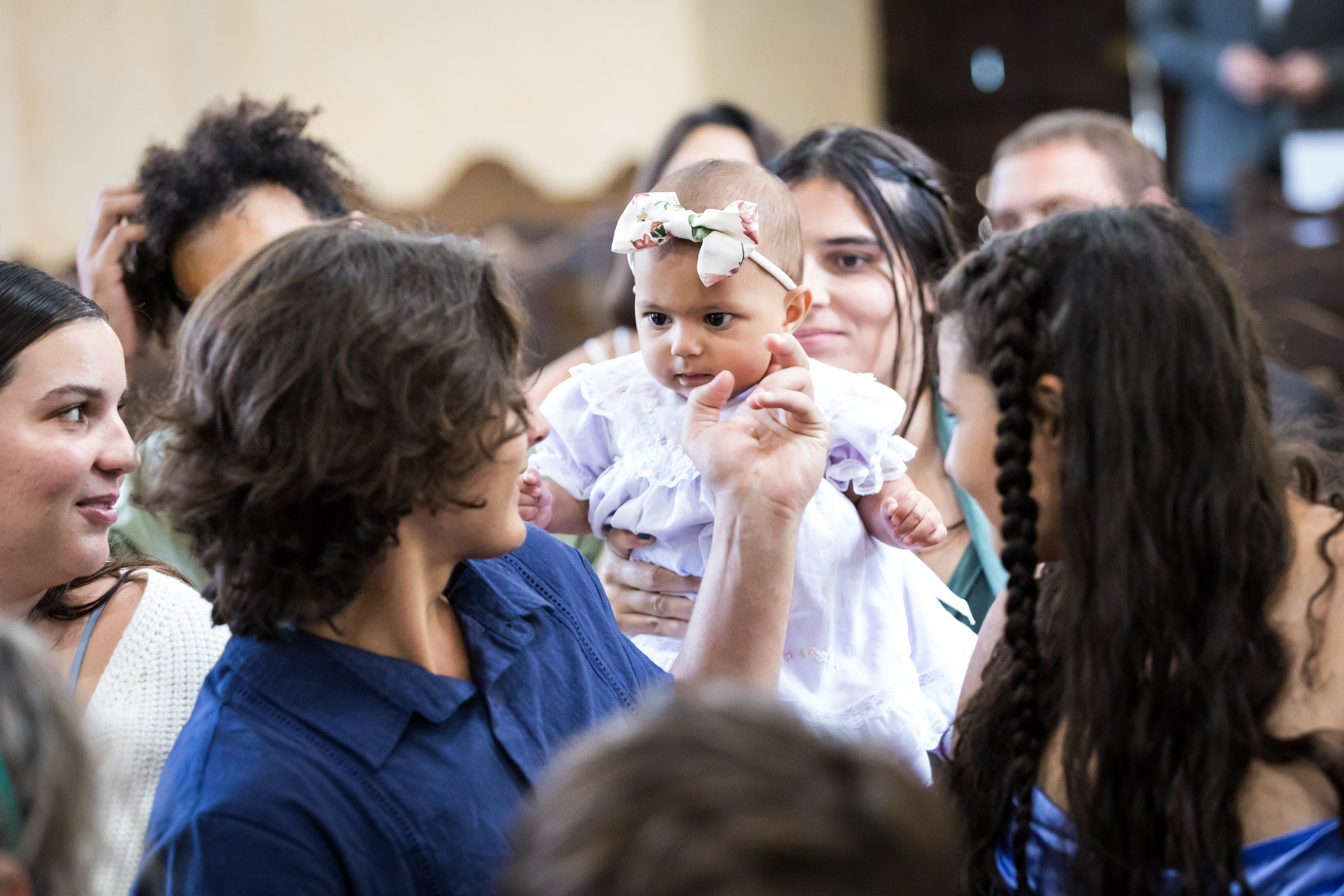 Male guest touching cheek of baby in pew behind him for an article on how to get married at Mission Espada