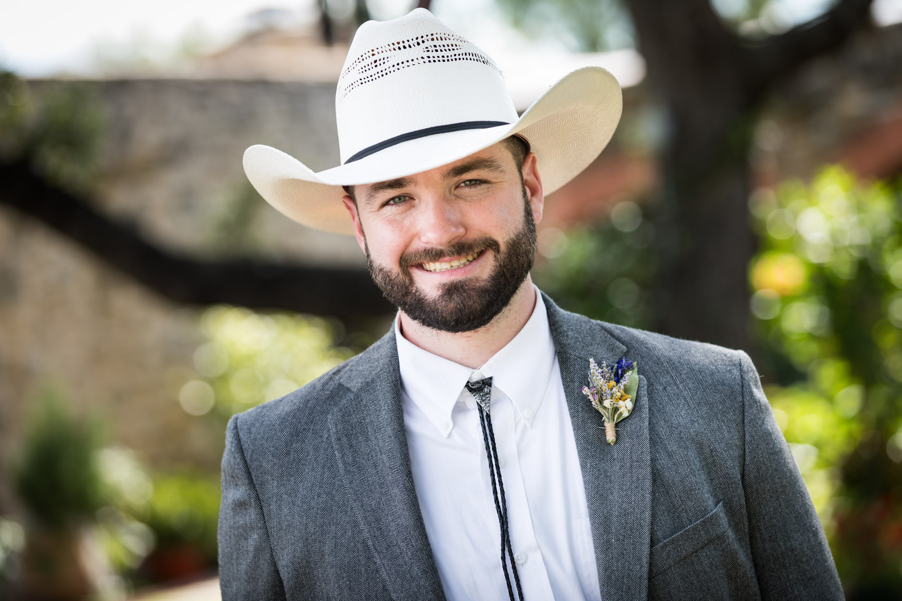 Groom with beard wearing cowboy hat for an article on how to get married at Mission Espada