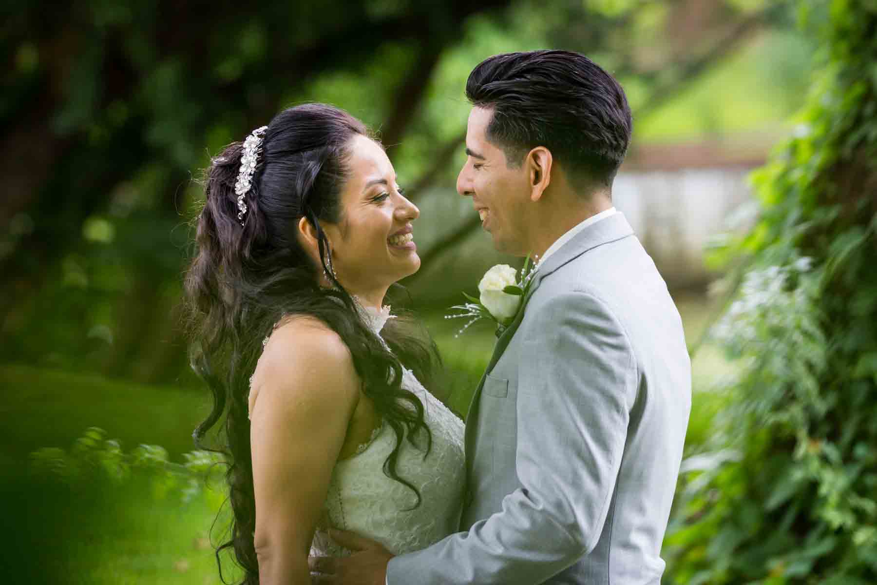 Bride and groom hugging in front of plants and trees for an article on how to have an eco-friendly wedding