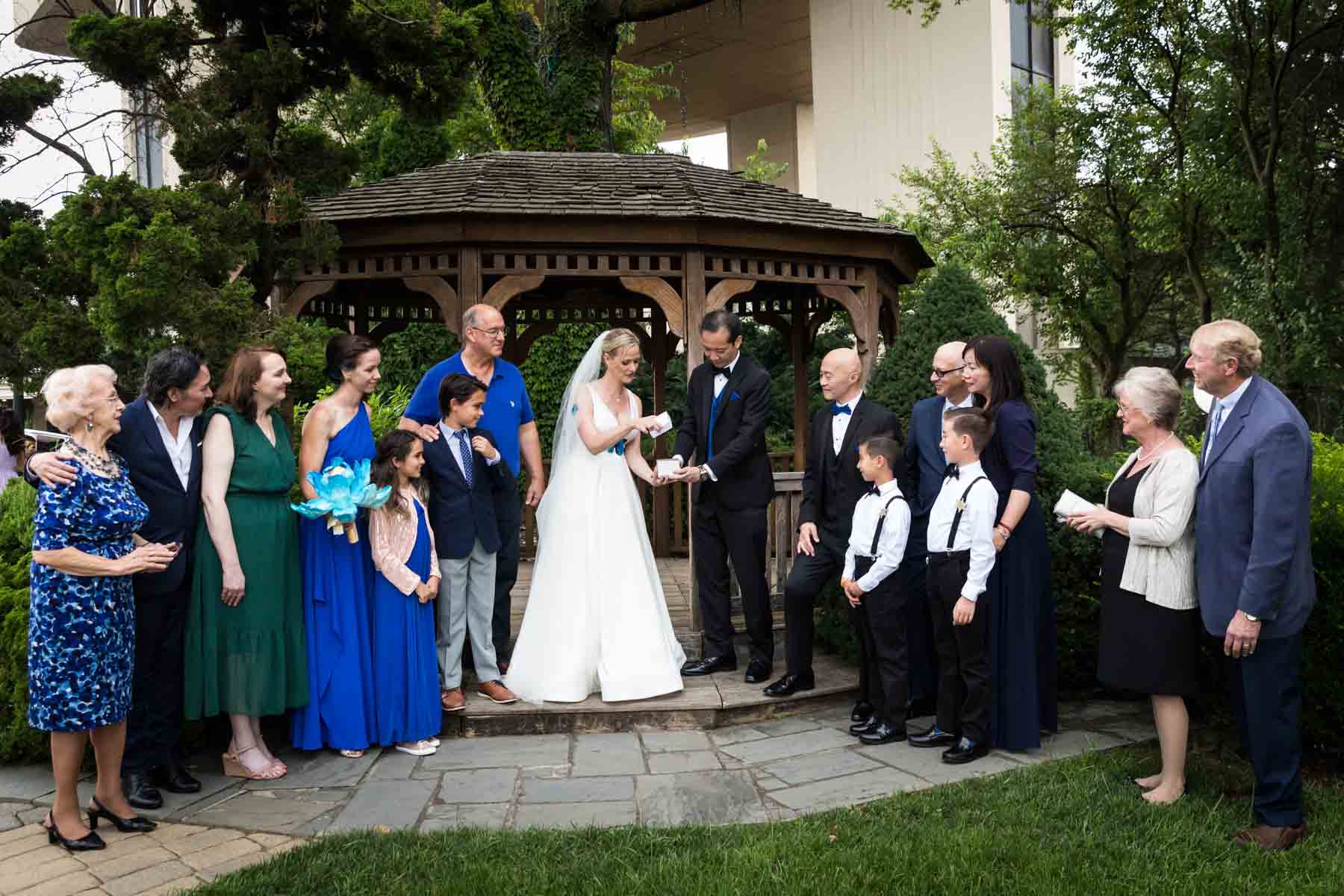 Butterfly release ceremony with bride and groom in front of bridal party and wooden gazebo