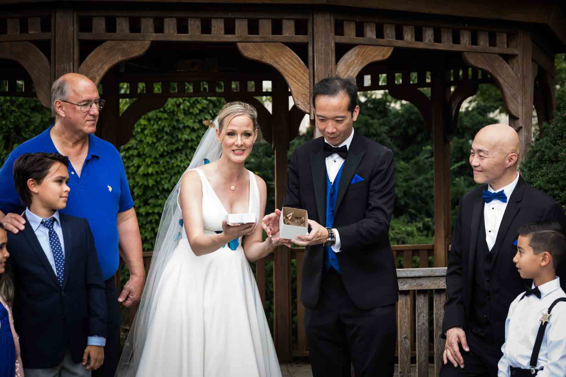 Butterfly release ceremony with bride and groom in front of bridal party and wooden gazebo