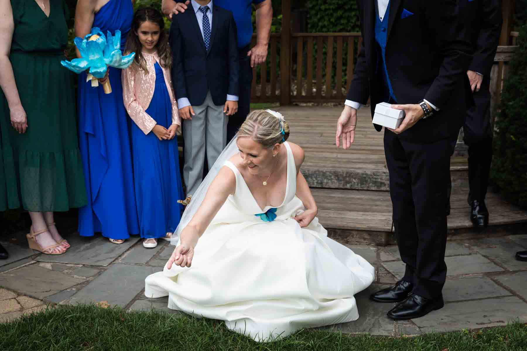 Butterfly release ceremony with bride sitting on ground putting out finger to touch butterfly