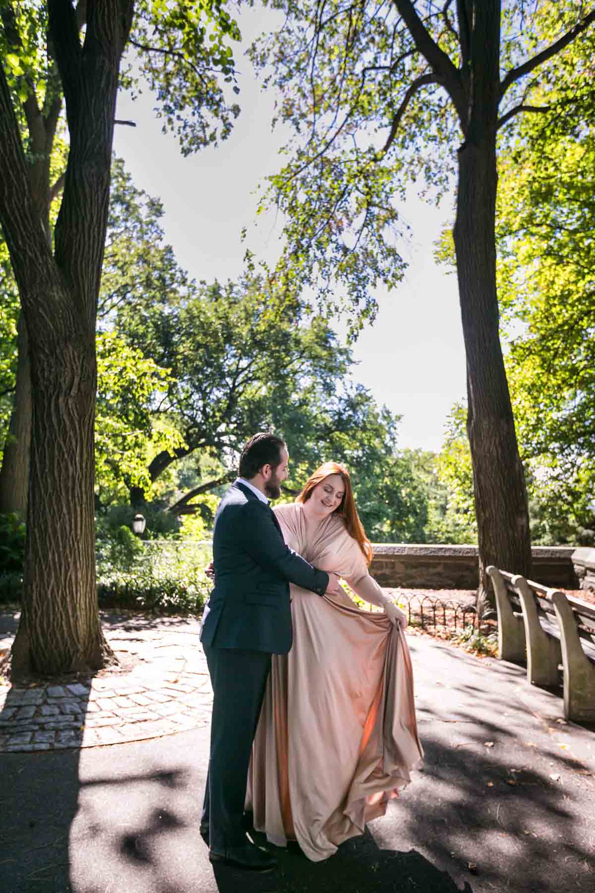 Bride and groom dancing in park with bride holding out pink dress for an article on how to have an eco-friendly wedding