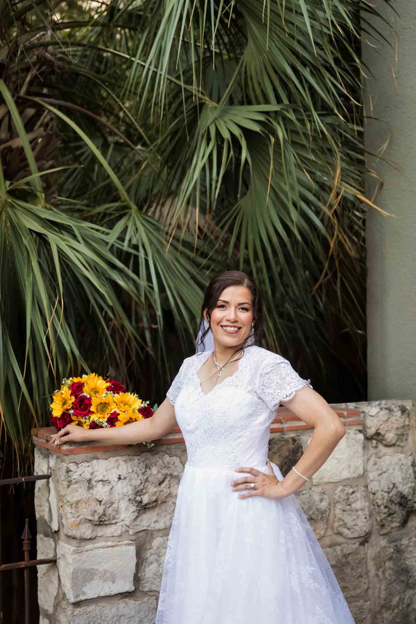 Bride wearing white dress and veil standing in front of palm trees