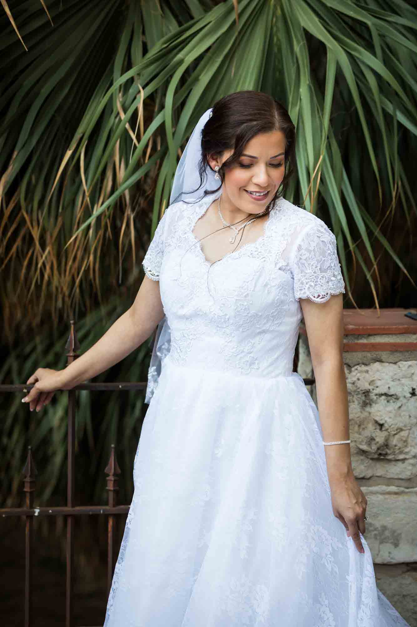 Bride wearing white dress and veil standing in front of palm trees