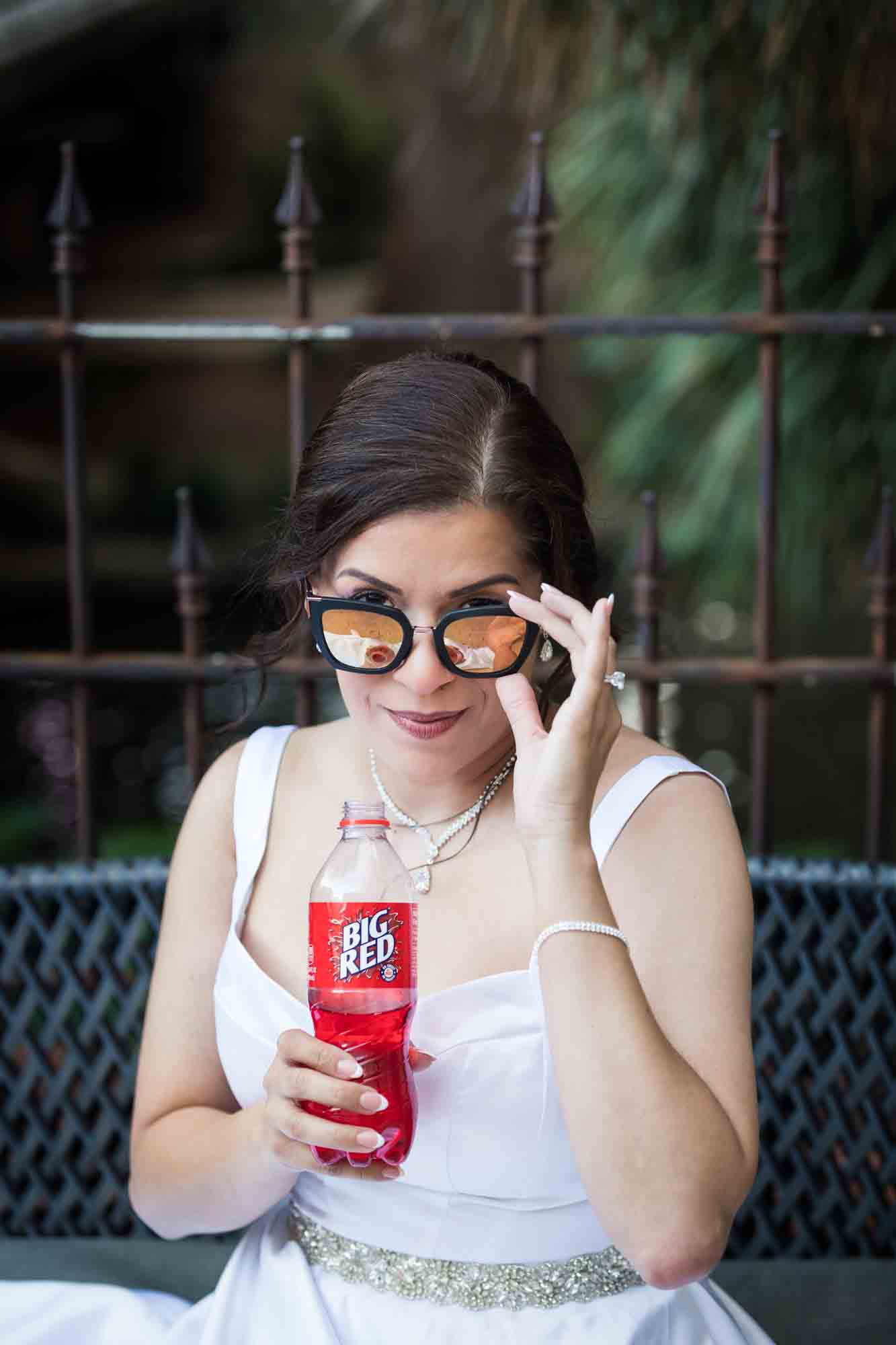 Bride holding Big Red soda bottle looking over sunglasses during a downtown San Antonio bridal portrait session